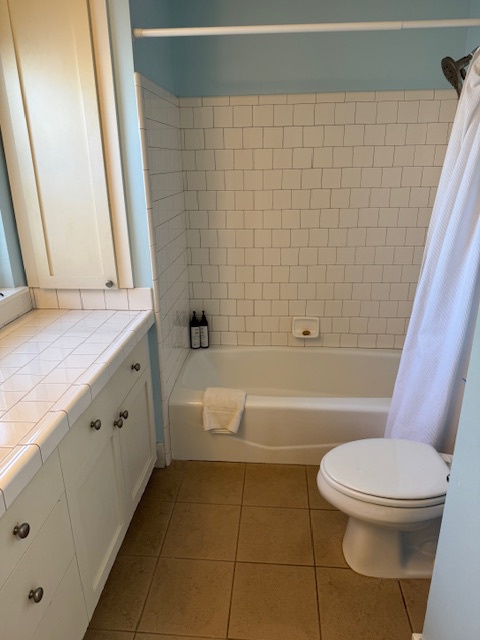 Princeville Vacation Rentals, Pili Aloha - Bathroom with a tub-shower combination, tiled walls, and a spacious countertop.