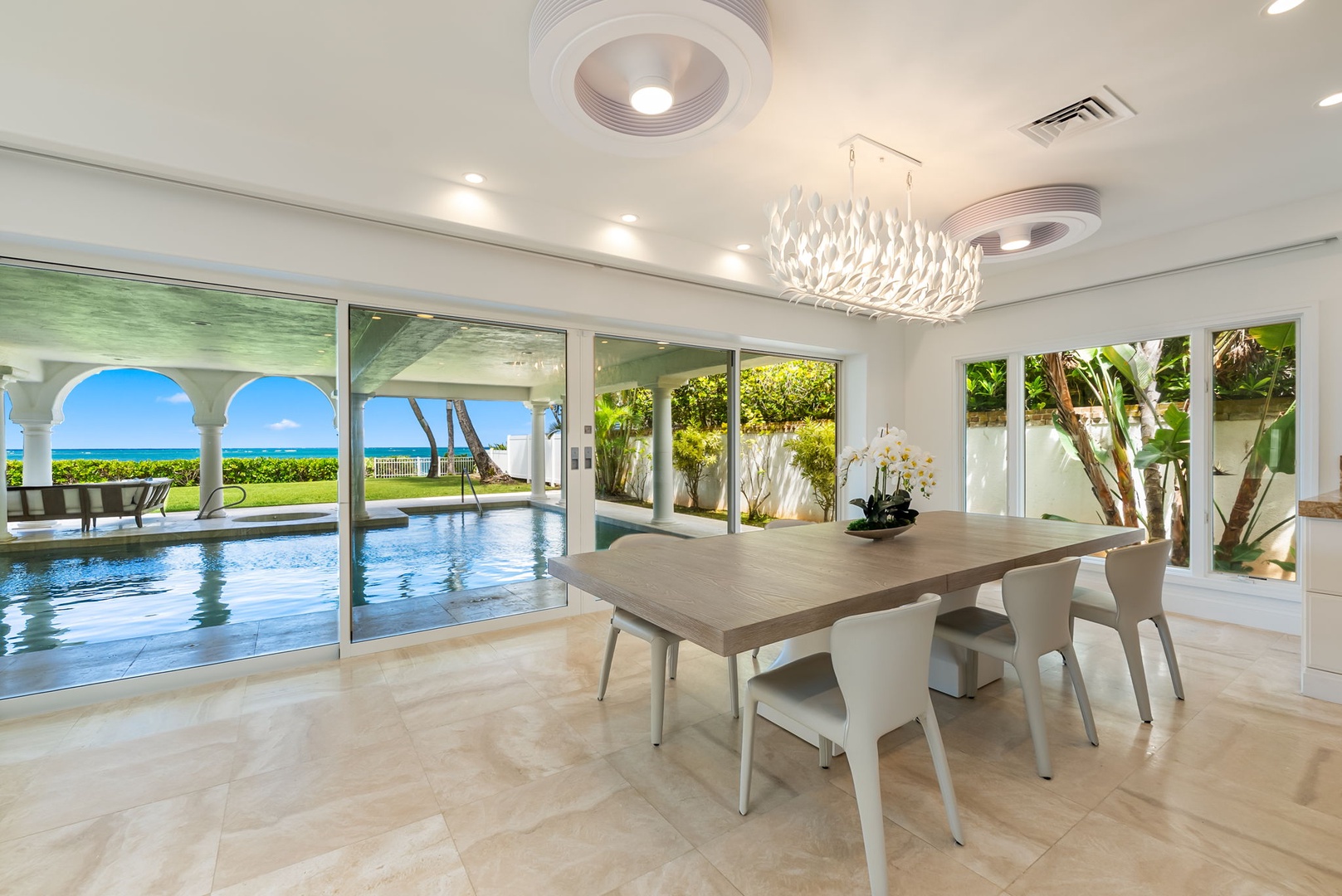 Kailua Vacation Rentals, Lanikai Sunrise Estate - Elegant formal dining room with chandelier lighting and pool views, designed for memorable gatherings.