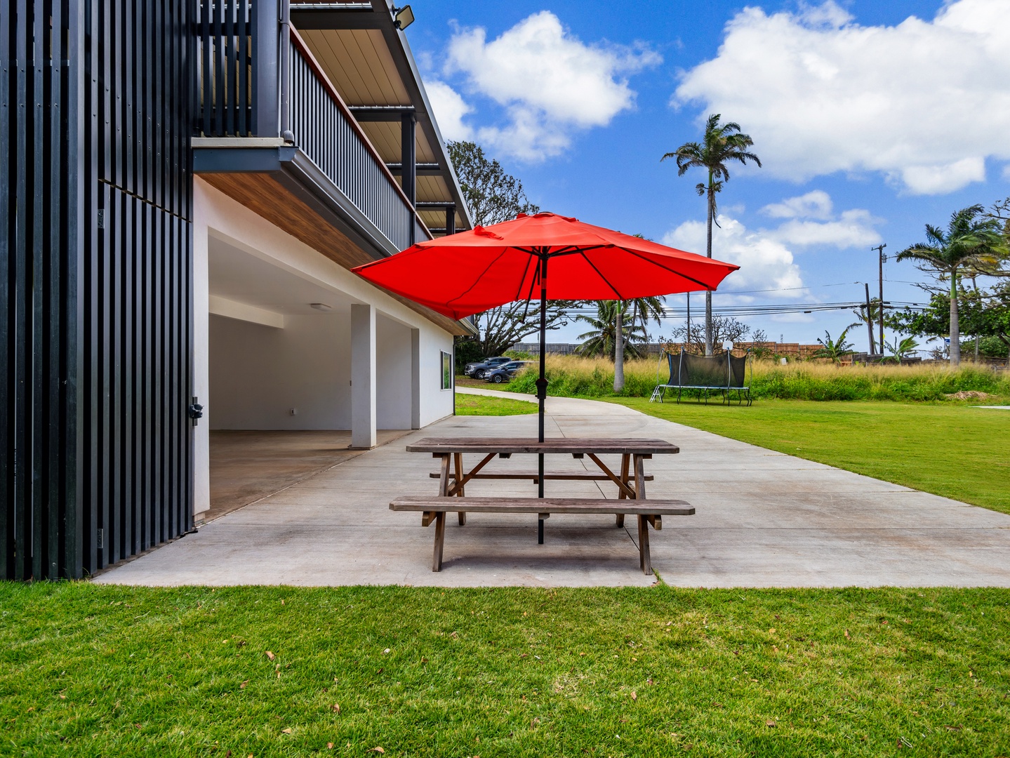 Haleiwa Vacation Rentals, Sunset Beach Island Retreat - A charming picnic area, complete with a vibrant red umbrella and a spacious table, invites guests to enjoy outdoor dining and relaxation amidst the beautiful surroundings.