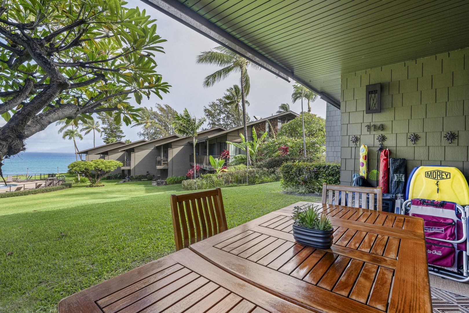 Lahaina Vacation Rentals, Polynesian Shores 114 - The covered lanai keeps the outdoor table shaded and comfortable, with the open lawn and ocean just beyond.