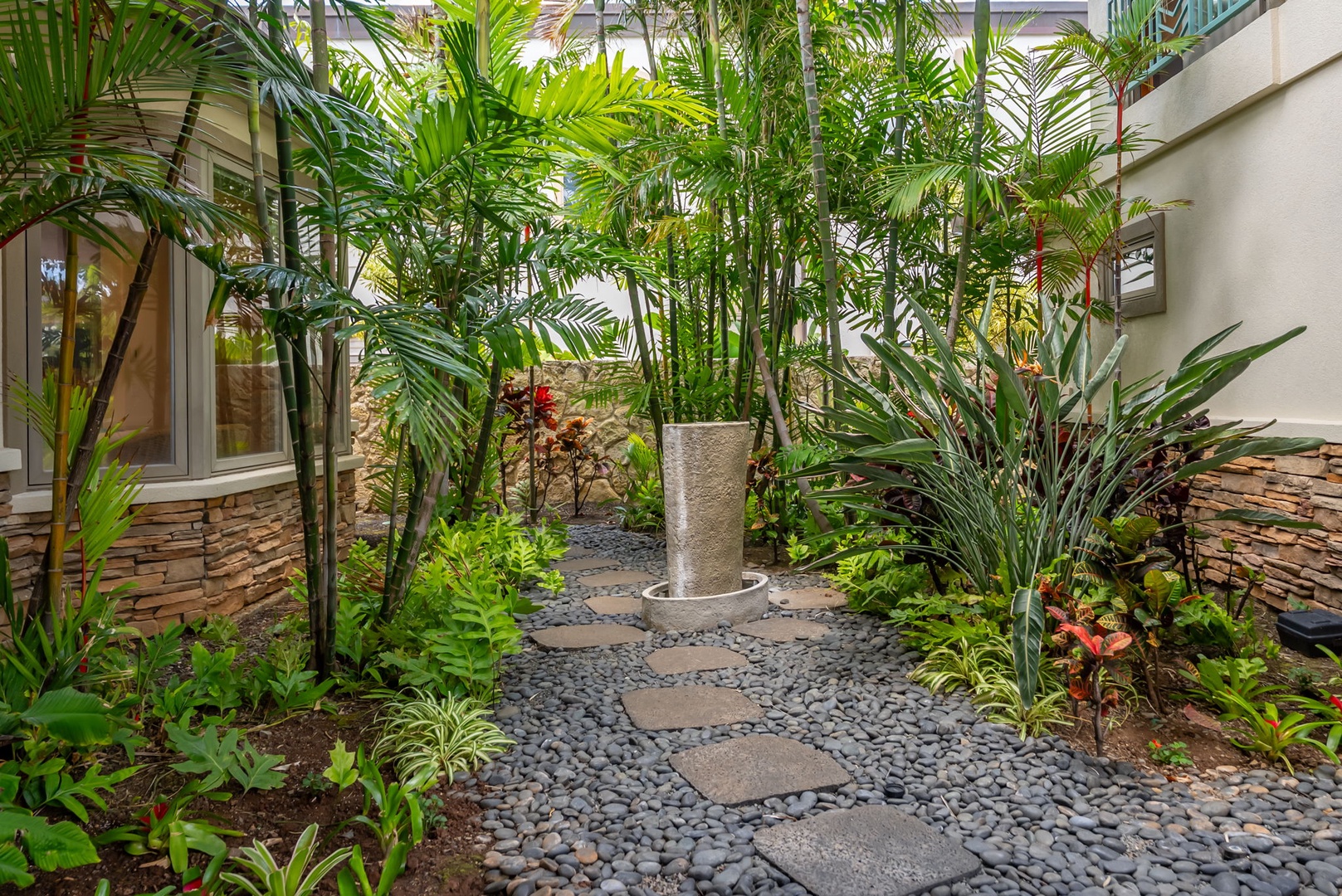 Honolulu Vacation Rentals, Maunalua Estate - Stone pathways and vibrant palms create a serene garden setting tucked within the property grounds.