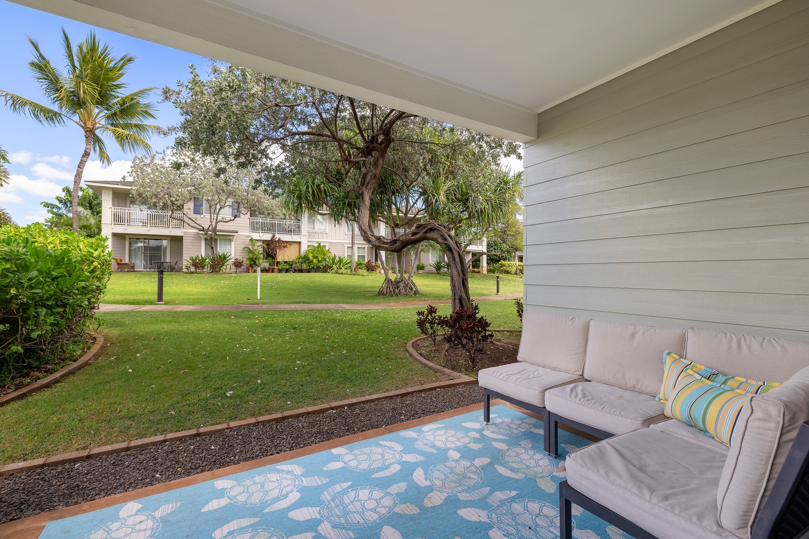 Private lanai overlooking lush green lawns and tropical landscaping, offering a quiet spot to unwind outdoors.
