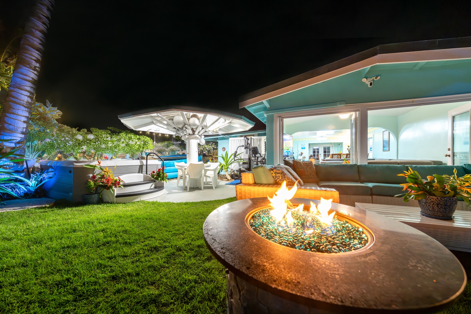 Hauula Vacation Rentals, Private Beach Paradise - After dark, the fire pit glows on the lawn while the house lights up behind.