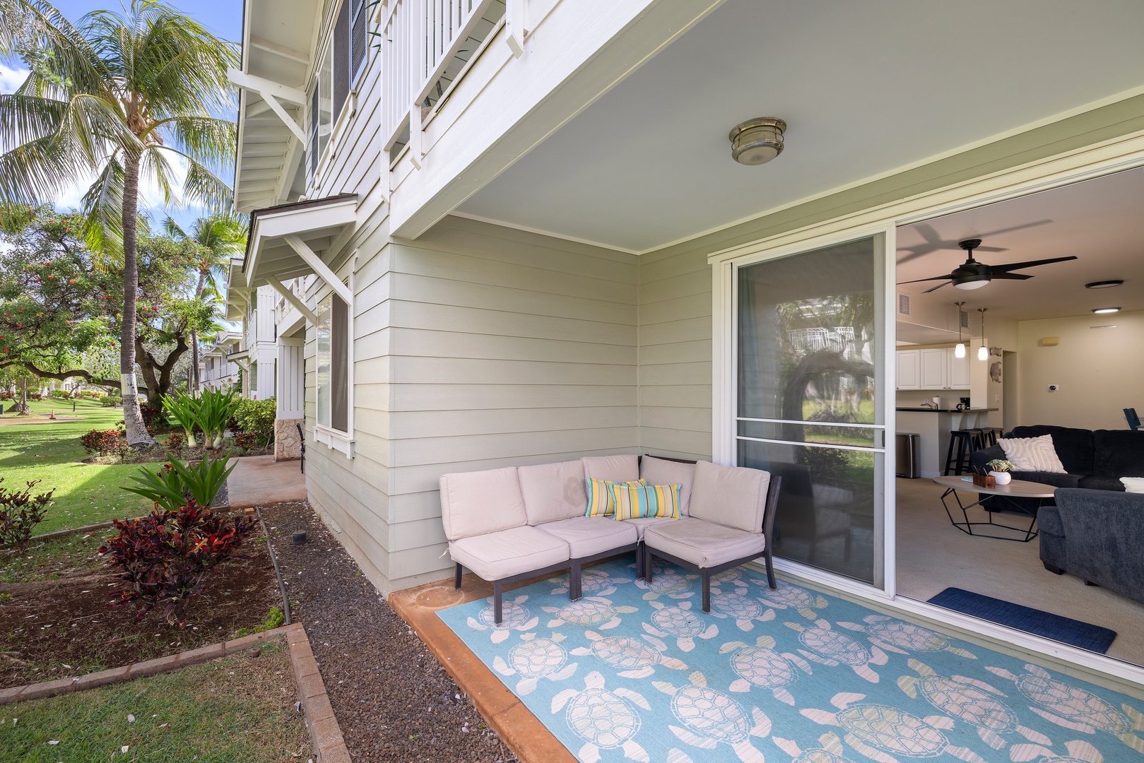 Ground-floor lanai with comfortable seating, perfect for morning coffee while enjoying peaceful tropical garden surroundings.