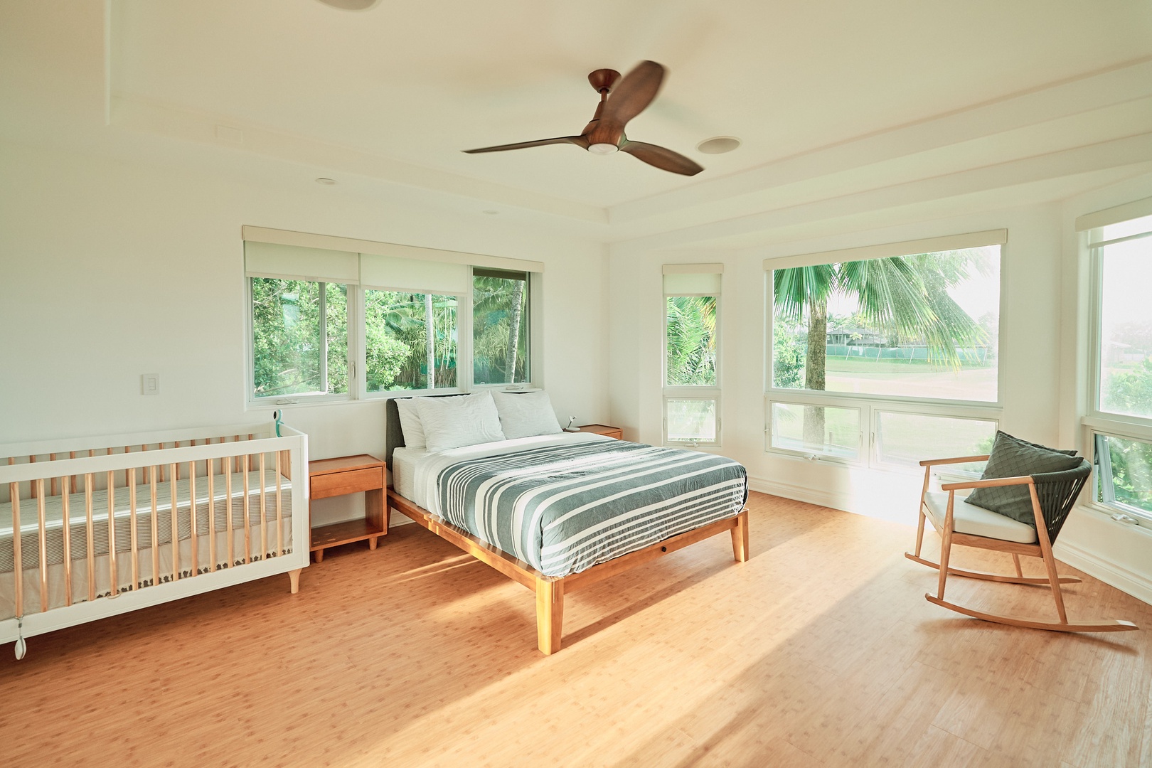 Princeville Vacation Rentals, Hale Kai - Wake up to tropical views through floor-to-ceiling windows in this bright bedroom, complete with a cozy crib for your little one.