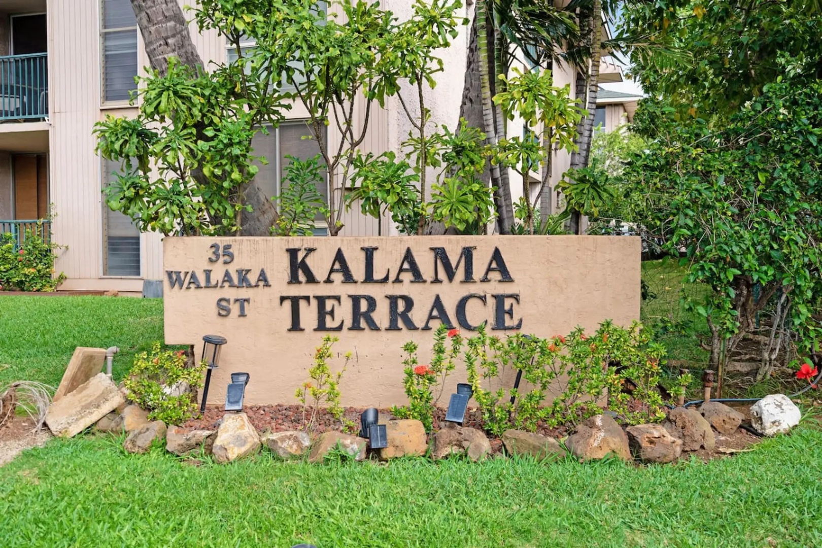 Kihei Vacation Rentals, Kalama Terrace P302 - The Kalama Terrace sign marks the turn in, tucked behind hibiscus and lava rock landscaping.