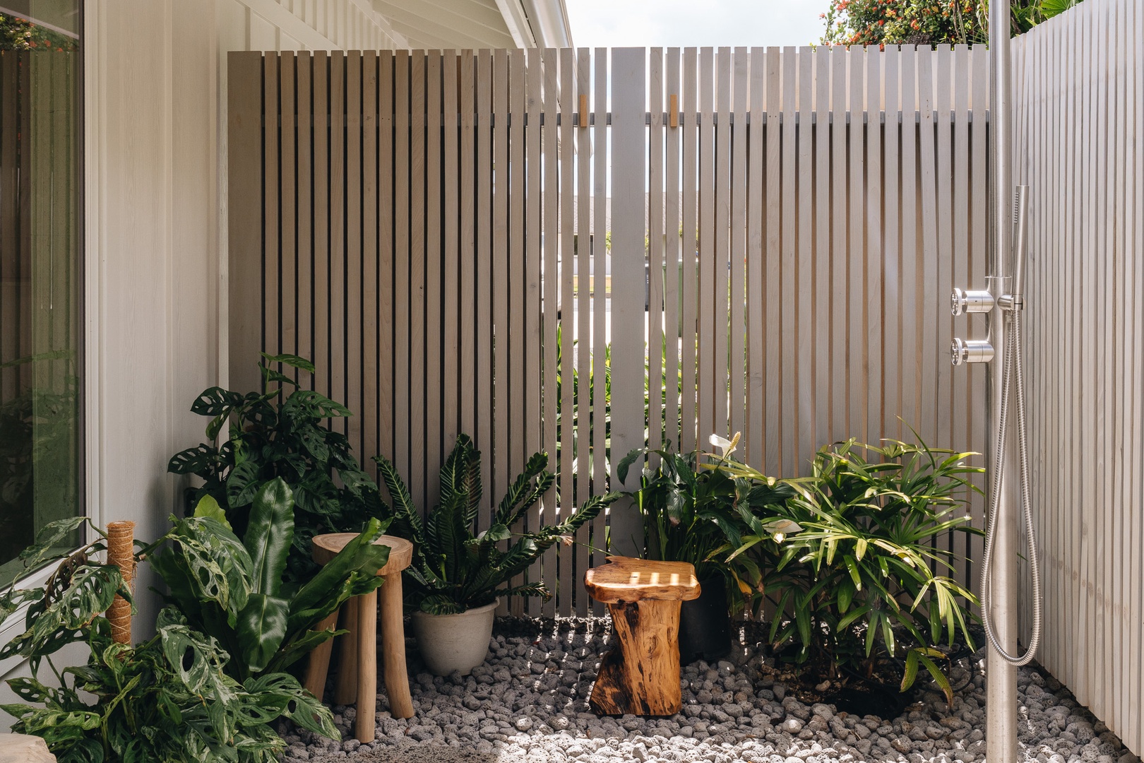 Honolulu Vacation Rentals, Surfside Bungalow** - A private outdoor shower surrounded by tropical greenery and natural stone.