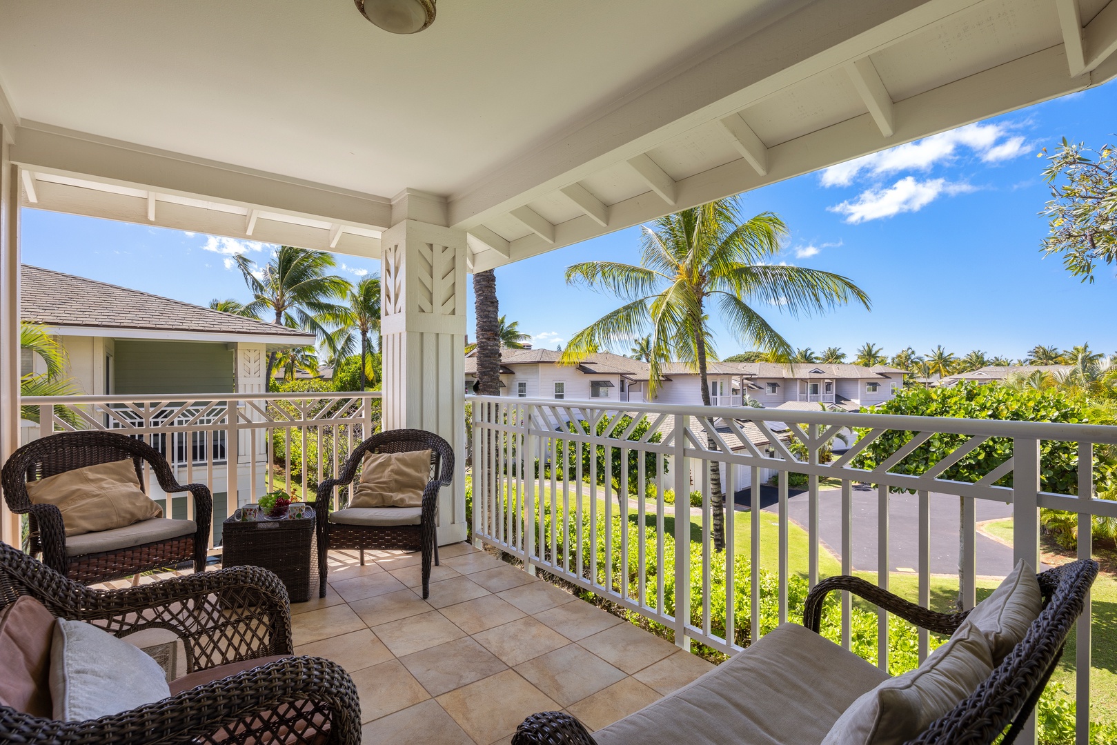 Unwind on your private covered lanai with comfortable wicker seating, overlooking tropical palms and lush gardens under endless blue skies.