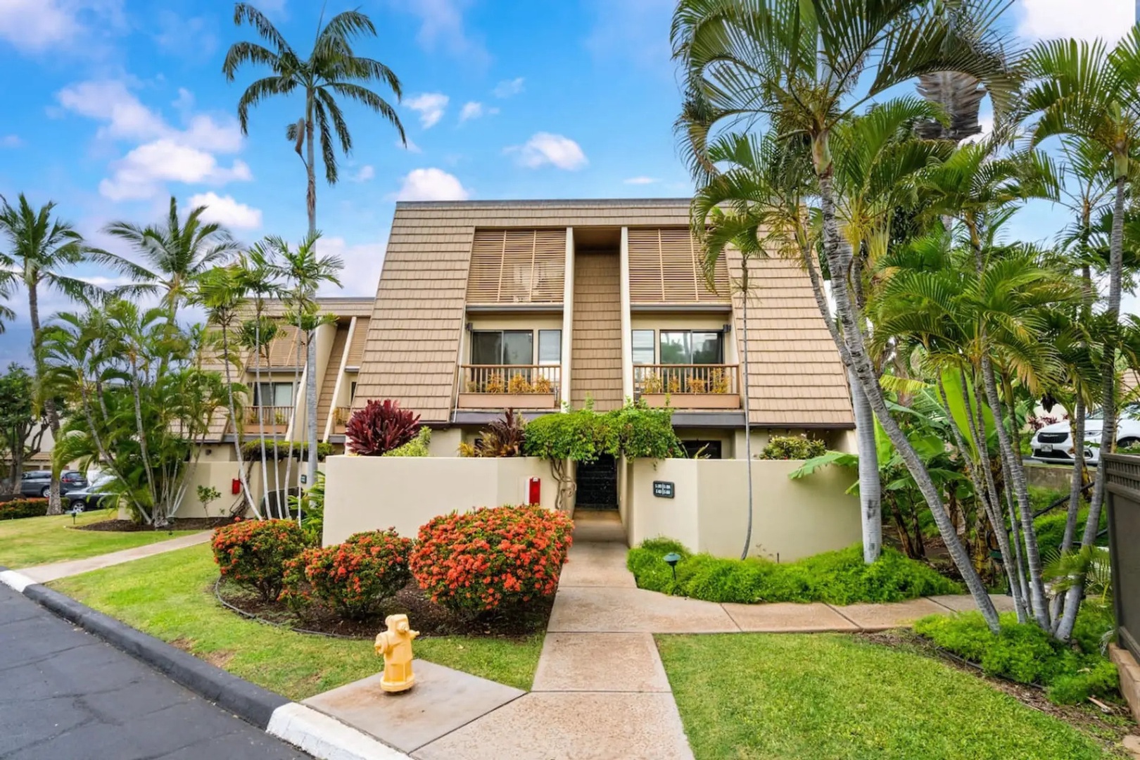 Kihei Vacation Rentals, Maui Kamaole E103 - A walkway leads straight to the door, palms marking the entrance from above.