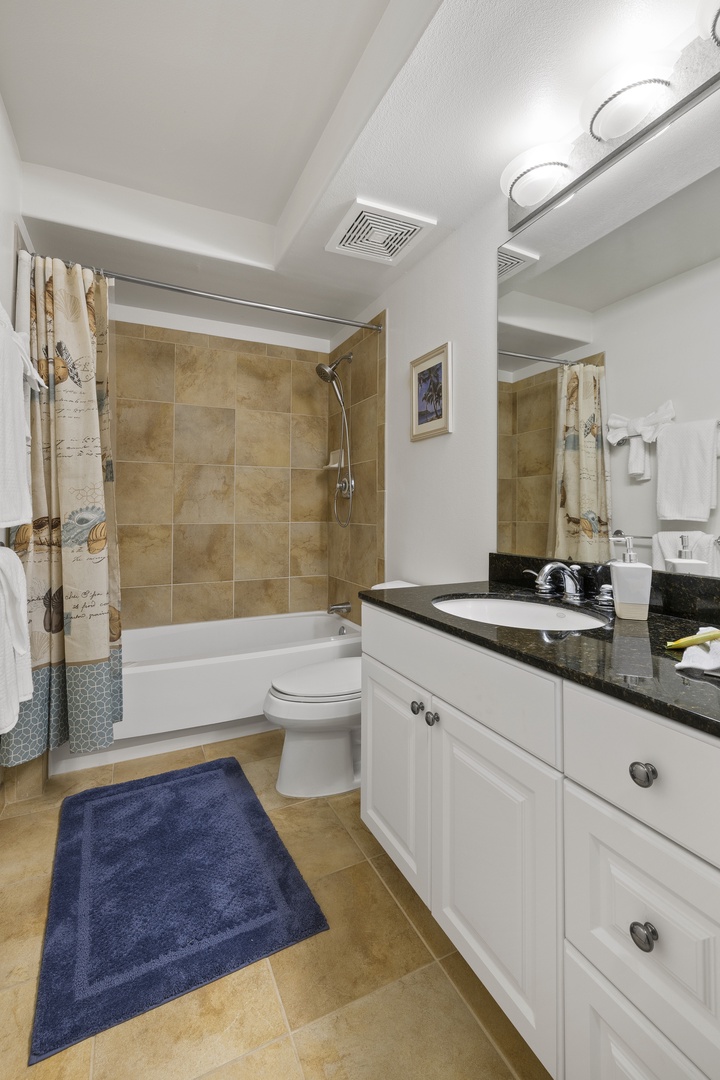 Freshen up after a day at the beach in this well-appointed bathroom with a large vanity and shower-tub combination.