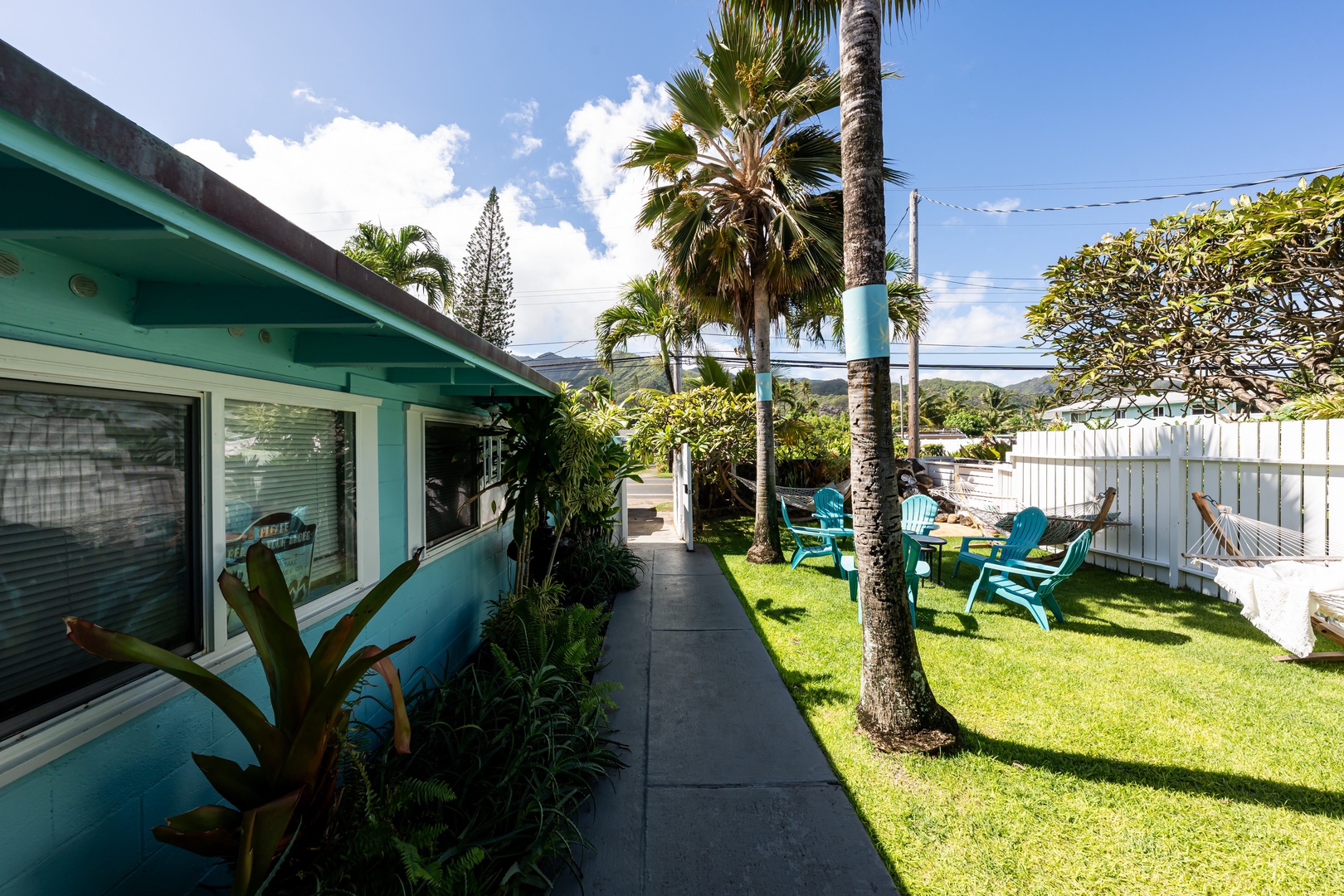Hauula Vacation Rentals, Private Beach Paradise - Tropical pathway lined with palms and vibrant greenery leading toward the ocean.