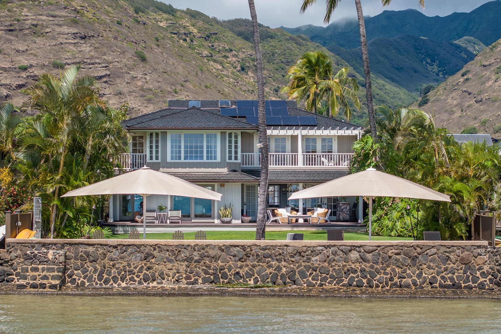Honolulu Vacation Rentals, Moana Lani - Main House - From the water, green ridges rise behind the house and its line of shade umbrellas.
