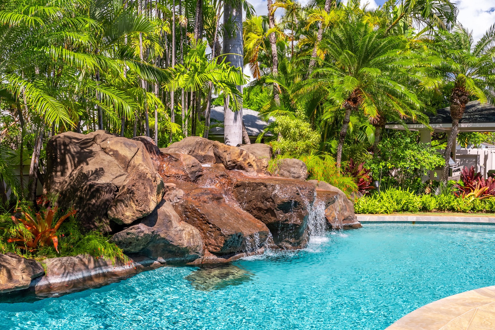 Honolulu Vacation Rentals, Kahala Oasis - Inviting pool with a natural rock waterfall feature, surrounded by lush greenery for a tropical retreat.