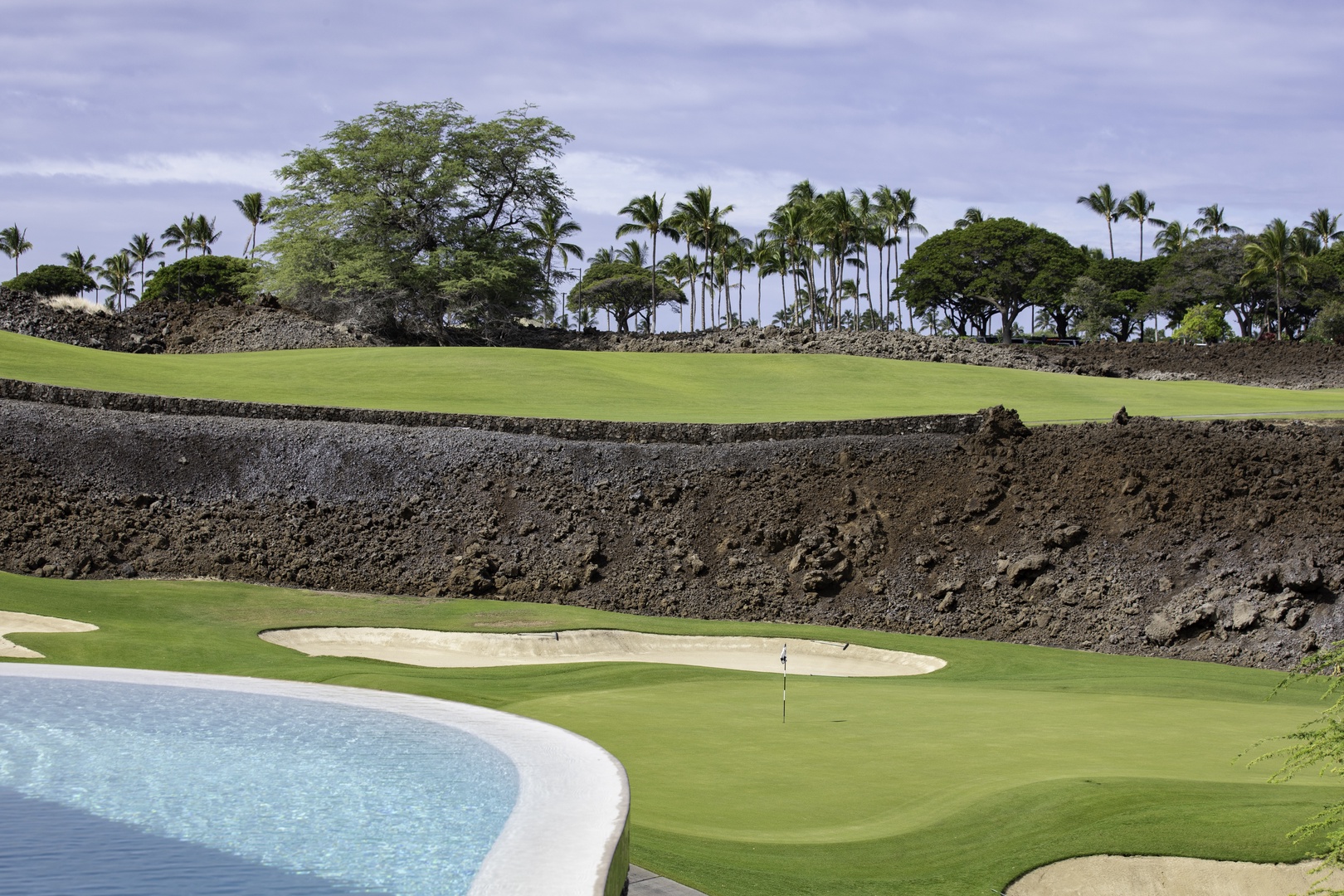Kamuela Vacation Rentals, Champion Ridge 7 - Championship golf course featuring pristine greens, strategic bunkers, and tropical landscaping with palm trees and volcanic rock walls.