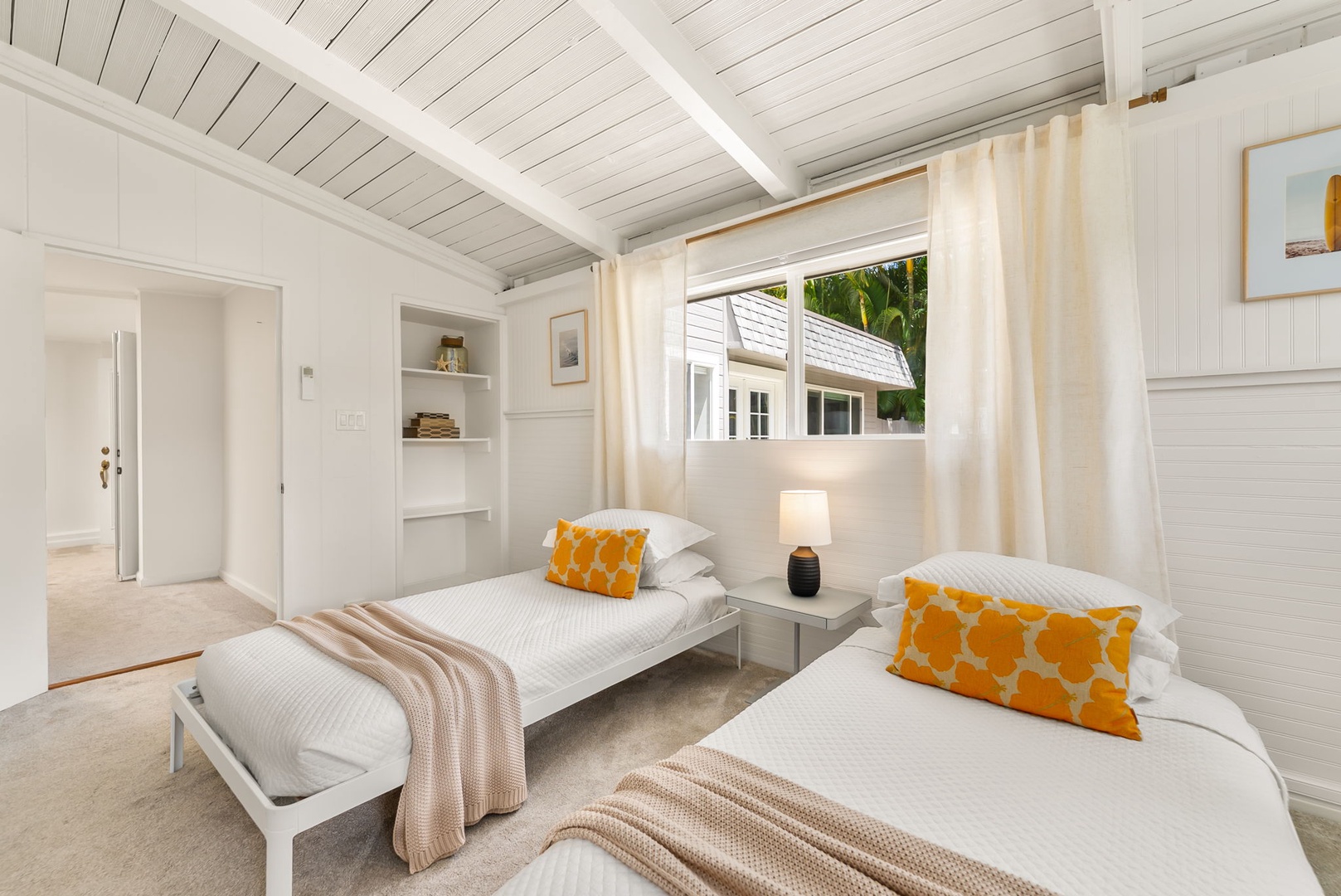 Honolulu Vacation Rentals, Ho'okipa Villa - Your bright twin bedroom offers soft white linens, pops of cheerful golden pillows, and built-in shelving for your essentials. Natural light fills the space through large windows framing tropical greenery.