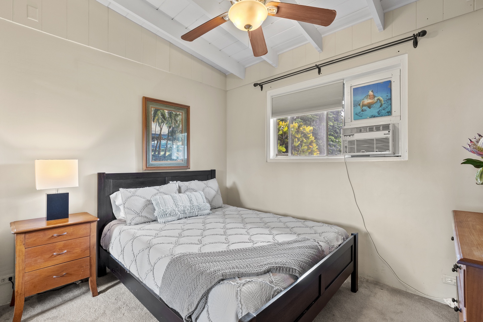 Haleiwa Vacation Rentals, North Shore Beachfront Resort - Cozy bedroom featuring a queen-size bed and charming artwork.