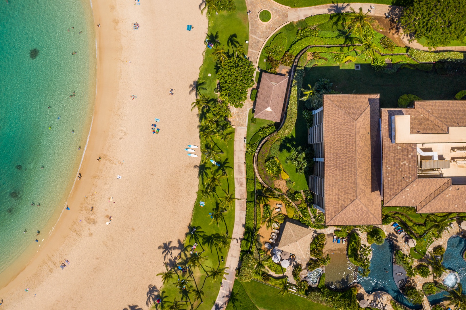 Overhead, a villa sits between the beach and its own green grounds.