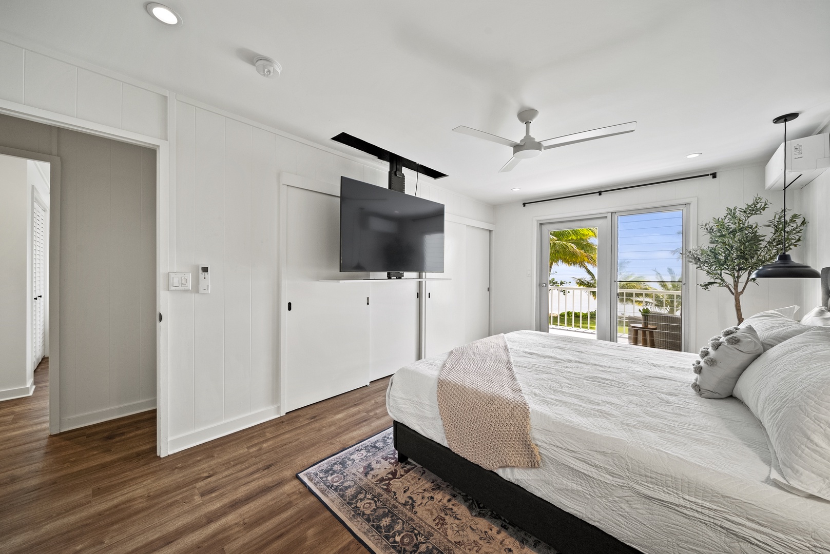 Honolulu Vacation Rentals, Honolulu Beachfront Retreat - Primary suite with a king-sized bed, ceiling-mounted TV, and lanai access, offering luxurious relaxation after beachfront adventures.
