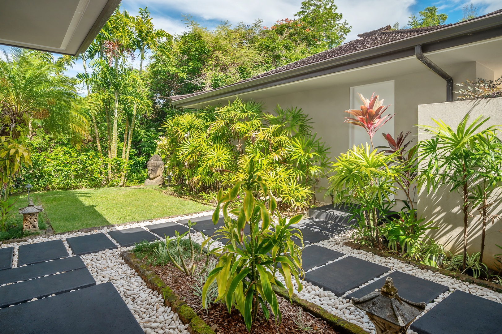 Princeville Vacation Rentals, Hanalei Plantation Villa - Tranquil garden pathway with lush tropical plants, perfect for a nature-filled stroll just outside your door.