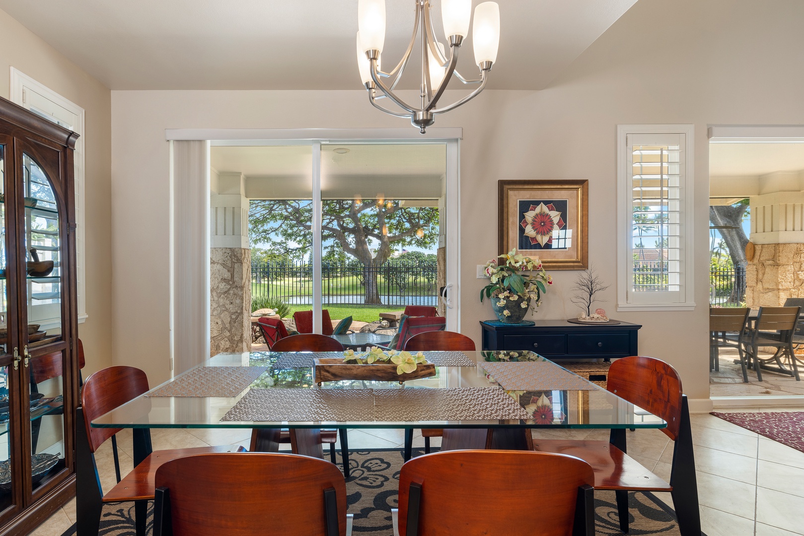 Gather around this elegant glass dining table where natural light streams through windows, creating the perfect space for memorable meals together.