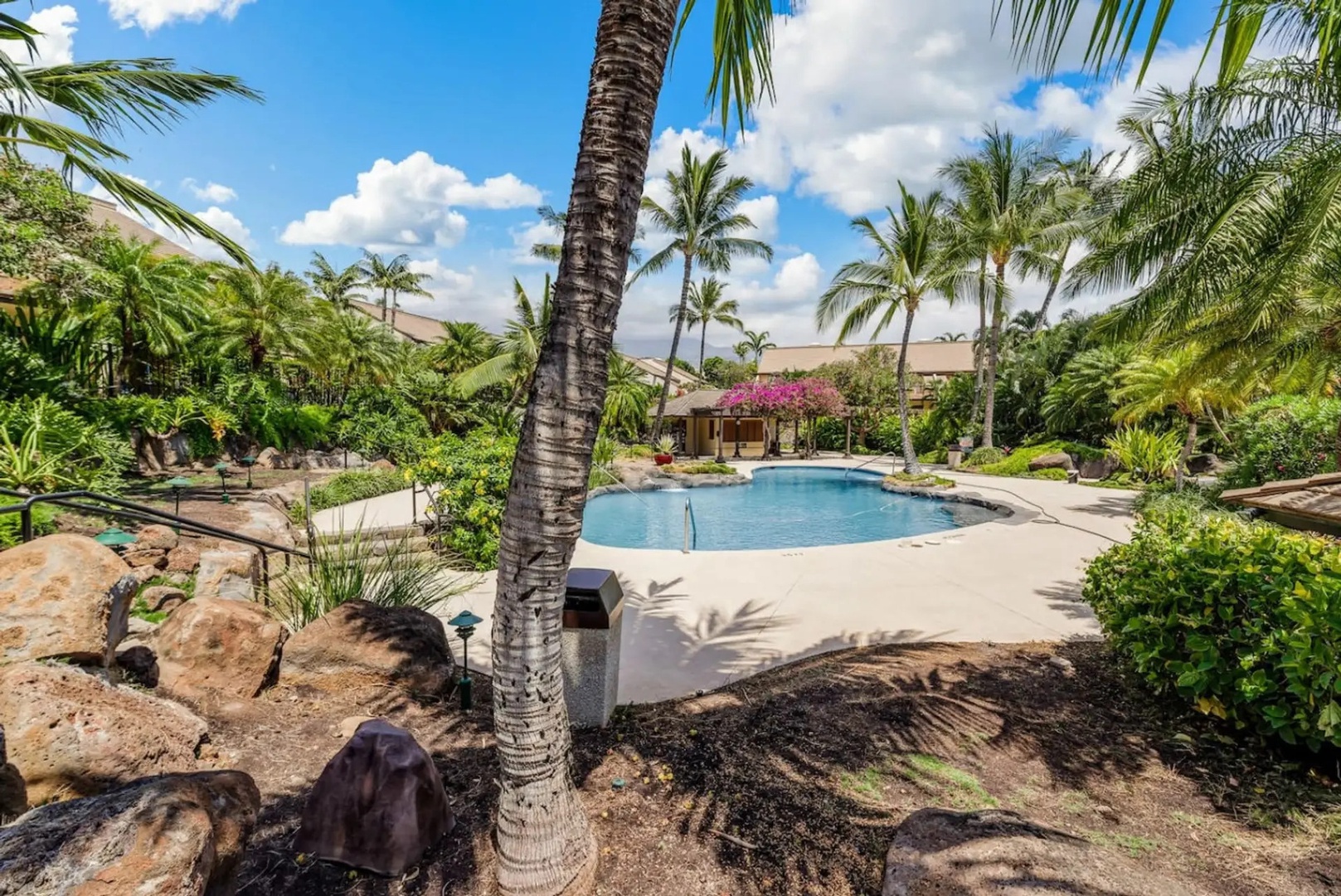 Kihei Vacation Rentals, Maui Kamaole E103 - The waterfall pool spills into its own rock grotto, framed by bougainvillea and palms.