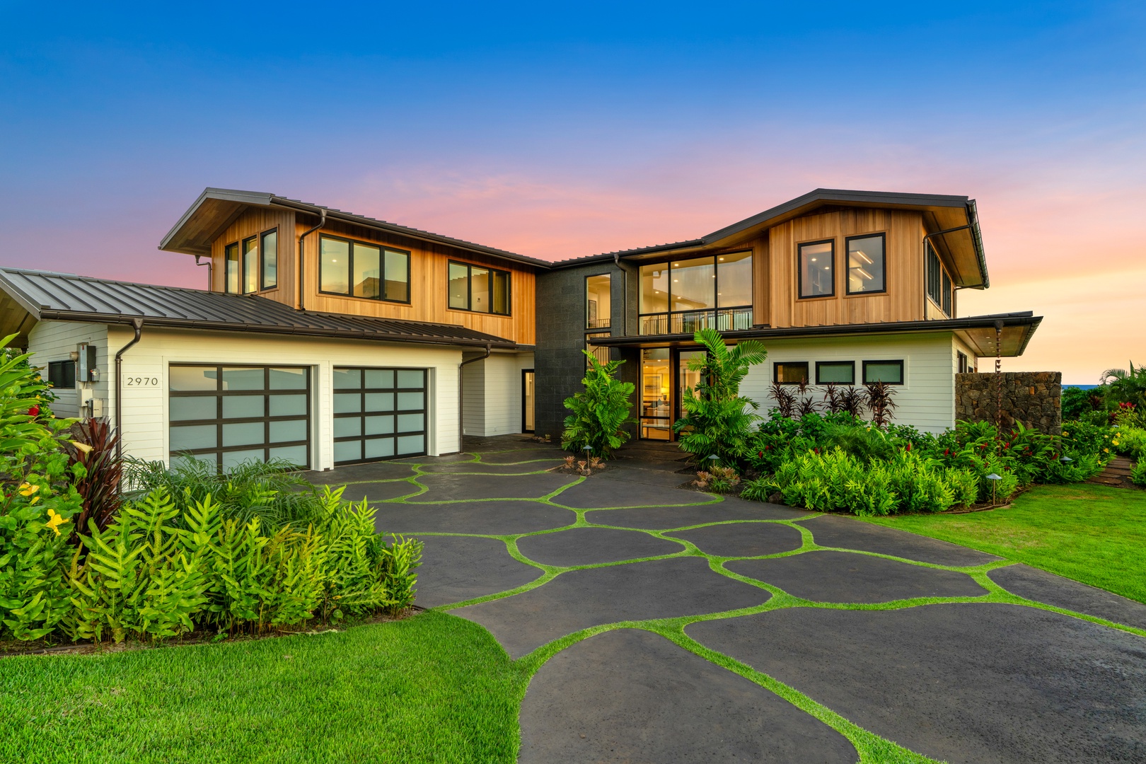 Koloa Vacation Rentals, Hale Laule'a at Kukui'ula - Modern architectural elegance awaits at this stunning property, featuring sleek design elements and beautiful landscaping against a colorful evening sky.