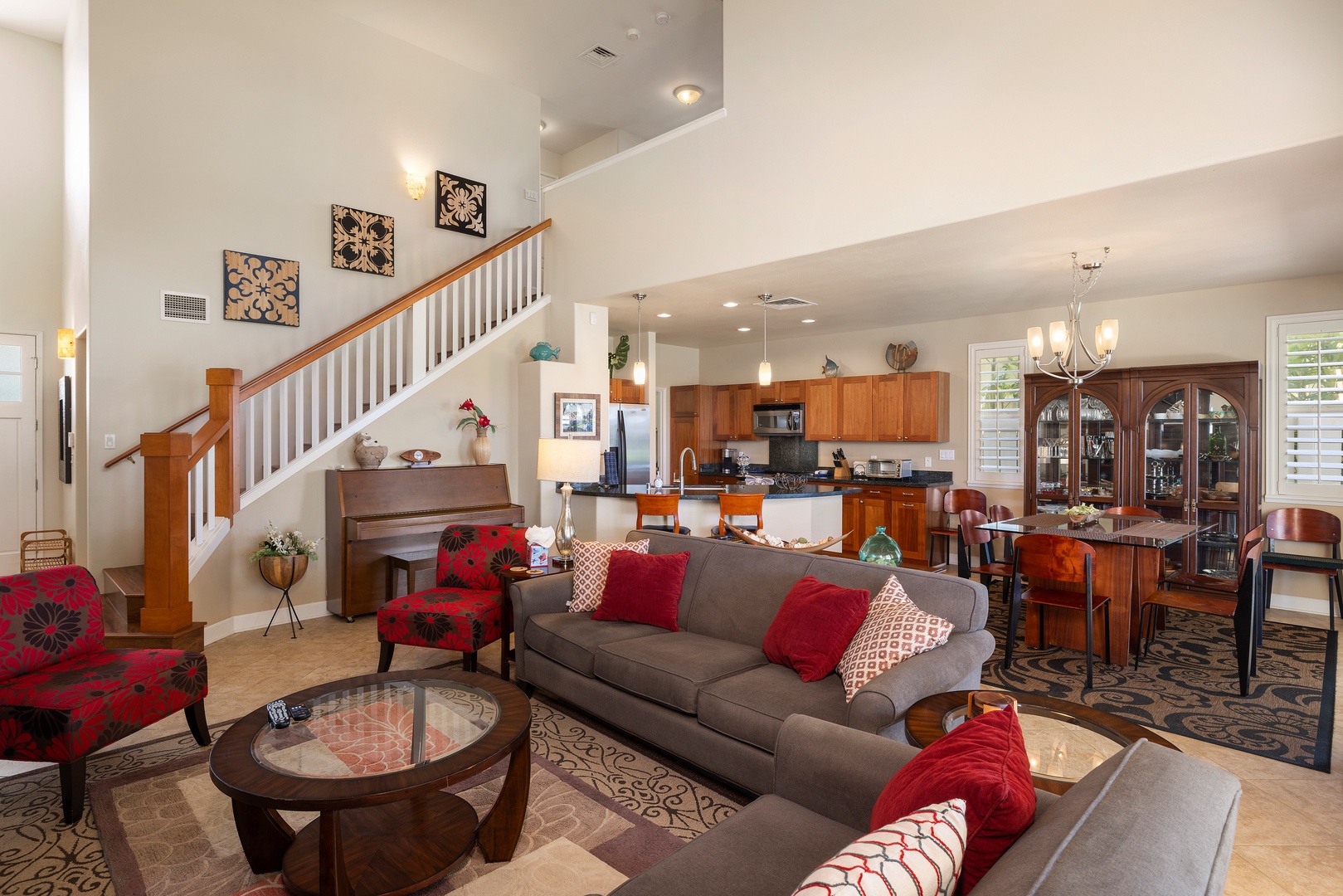 Relax in your spacious open-concept living area with plush gray sofas, vibrant red accents, and a fully equipped kitchen perfect for family gatherings.