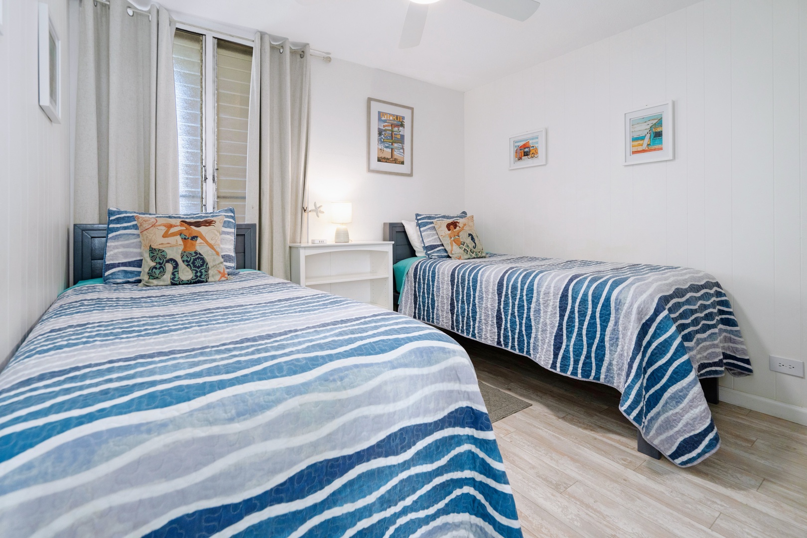 Kihei Vacation Rentals, Punahoa Beach 205 - Twin beds sit side by side beneath framed Maui prints, a lamp glowing on the nightstand between them.