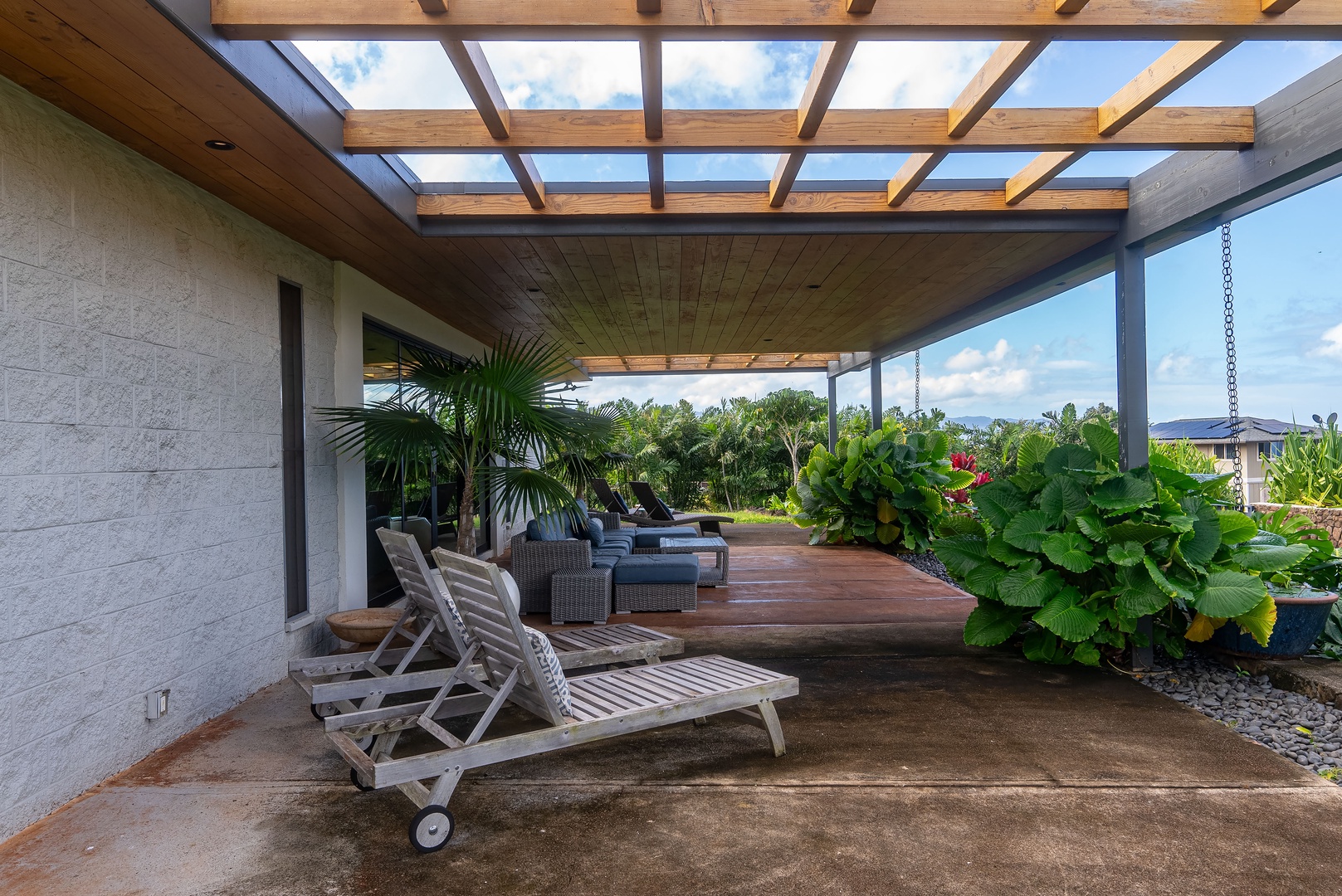 Haleiwa Vacation Rentals, Hale Mahina - Relax under this stylish pergola, surrounded by lush greenery and comfortable lounge seating for a peaceful outdoor retreat.