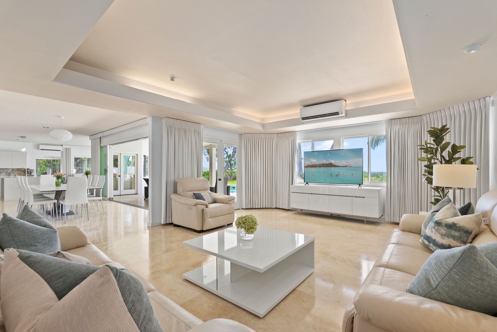 Honolulu Vacation Rentals, Paradise Beach Estate - Natural light fills the plush living room, where floor-to-ceiling glass connects indoor comfort to tropical serenity beyond.