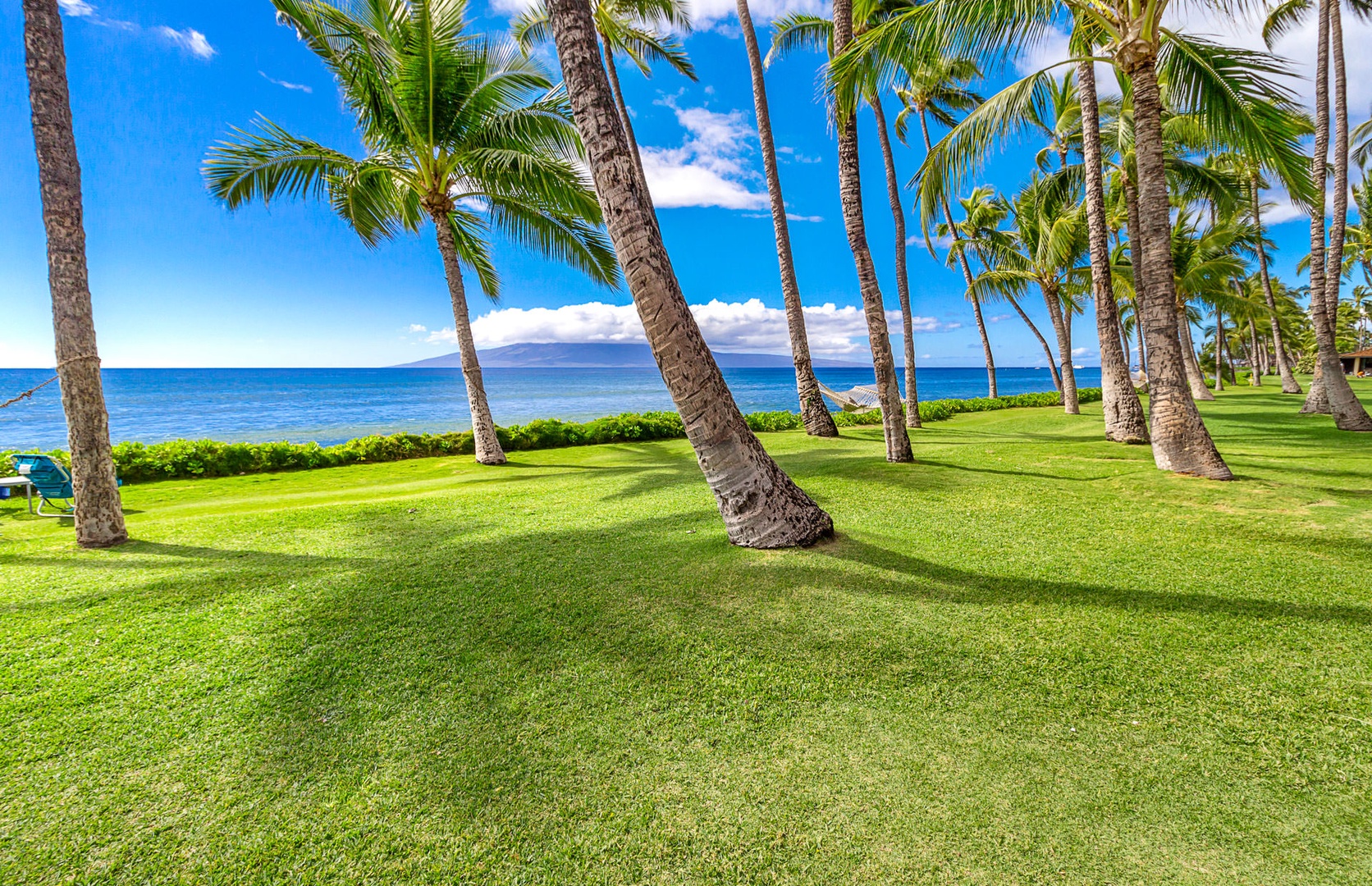 Lahaina Vacation Rentals, Puamana 240-3 - Immerse yourself in a tropical paradise with lush green lawns, swaying palm trees, and serene ocean views.