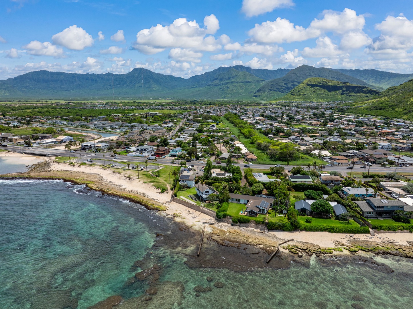 Waianae Vacation Rentals, Ma'ili Blue - Stunning aerial view showcases the oceanfront community nestled between crystal-clear waters and majestic mountains, with tropical homes scattered throughout the lush landscape.