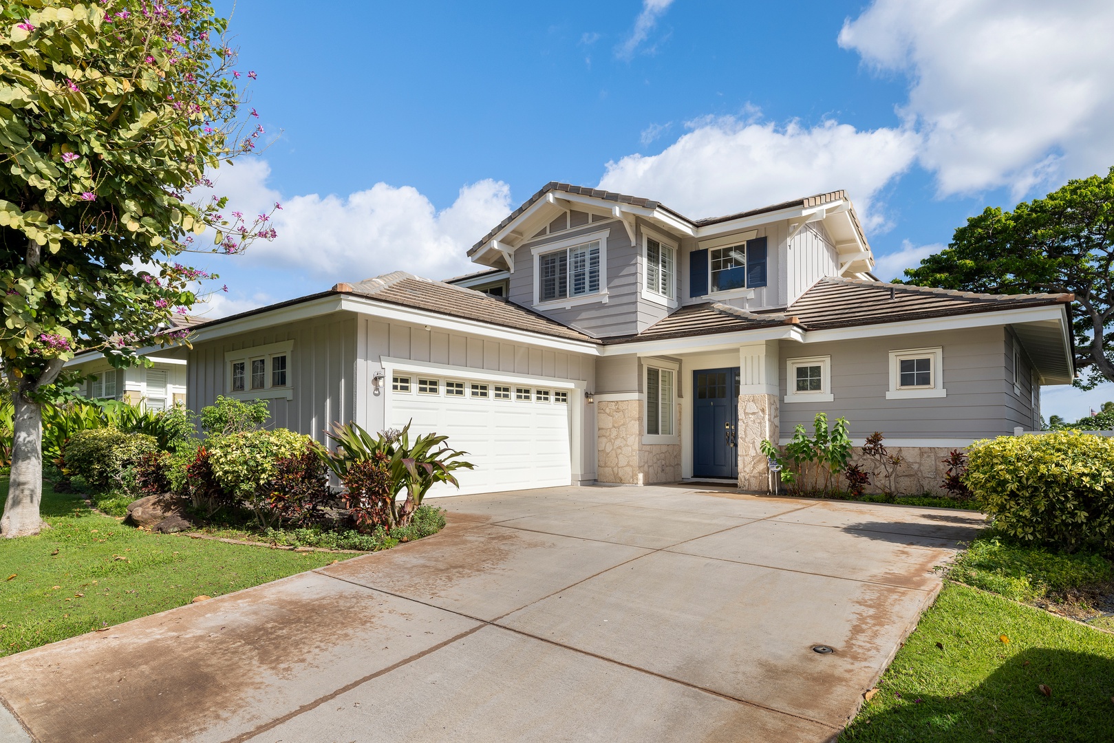 Beautiful two-story home with modern exterior, lush tropical landscaping, and convenient garage parking in a peaceful neighborhood setting.