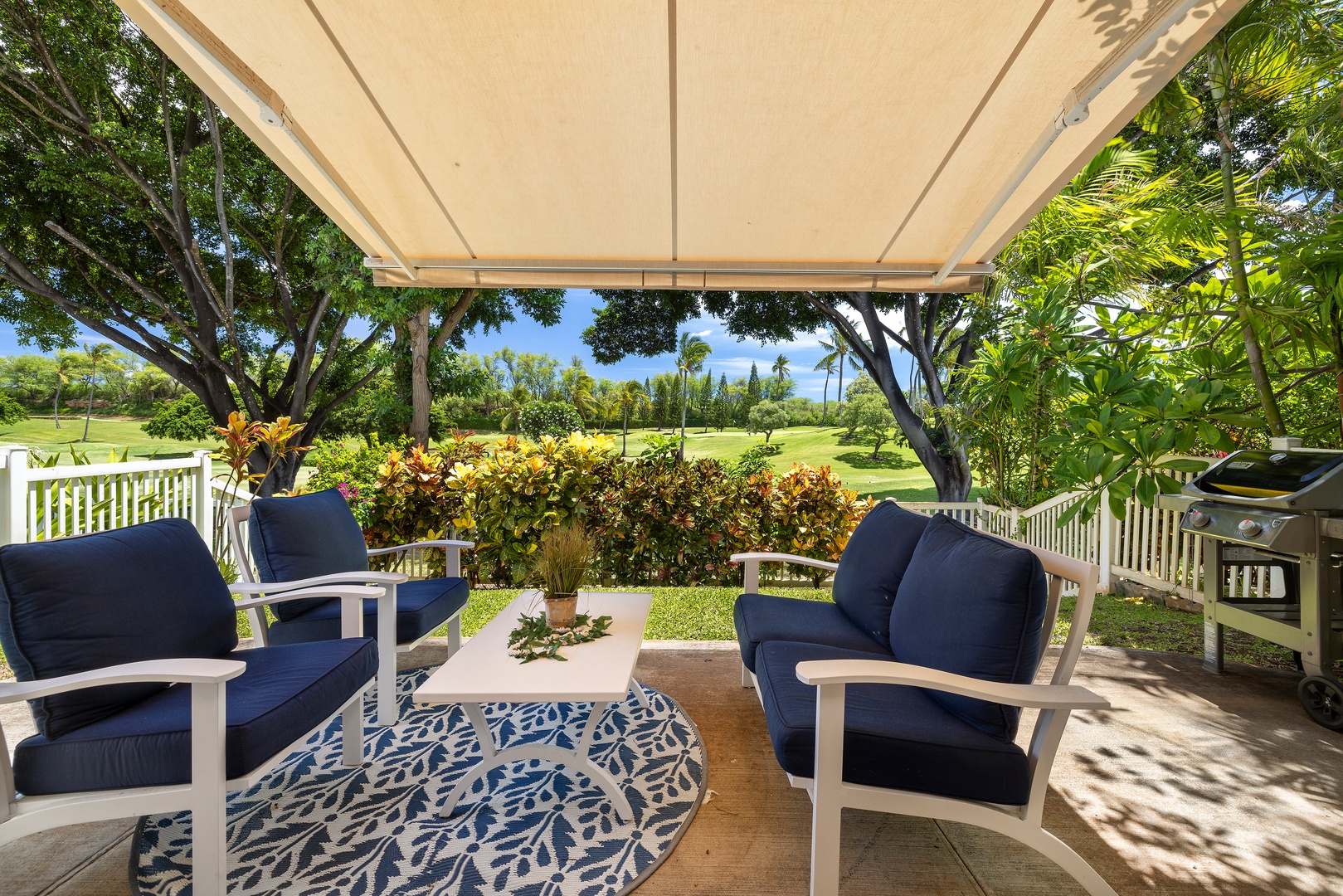 Your private patio offers shaded comfort with plush navy seating and garden views, perfect for morning coffee or evening relaxation.