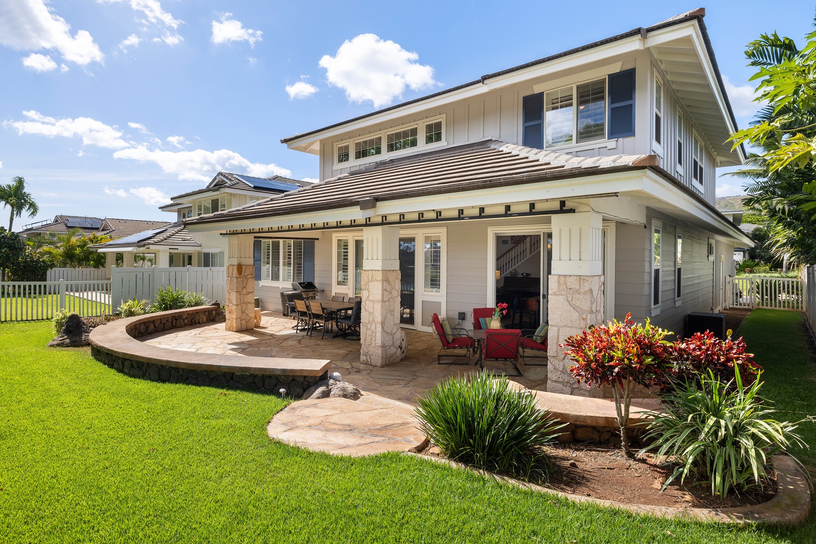 Beautiful two-story vacation home featuring covered lanai with outdoor dining and tropical landscaping in a peaceful residential setting.