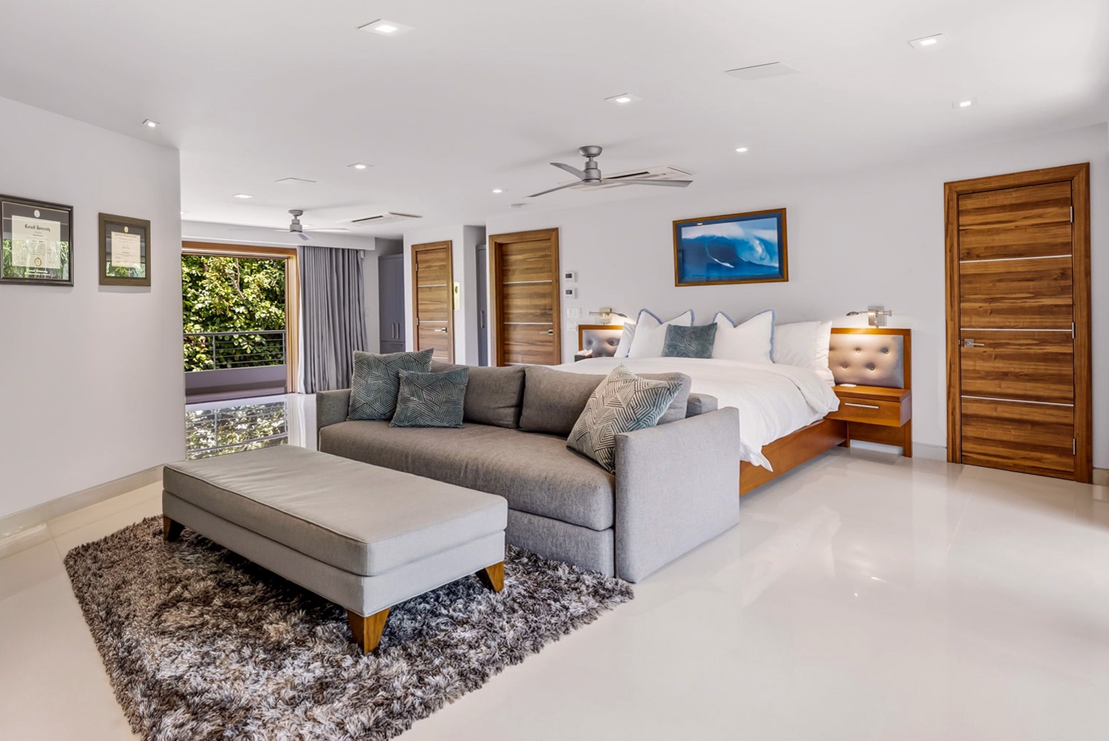 Honolulu Vacation Rentals, Diamond Head Beachfront Estate - Unwind in your spacious suite with a plush sofa, luxurious king bed, and modern design. Large windows frame lush garden views, while sleek wood accents and soft lighting create your perfect tropical retreat.