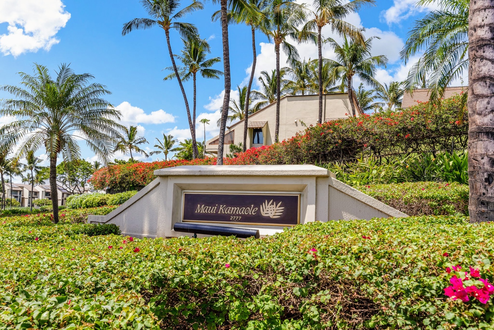 Kihei Vacation Rentals, Maui Kamaole E103 - Palms and bougainvillea frame the entrance sign, the first marker that you've arrived at Maui Kamaole.