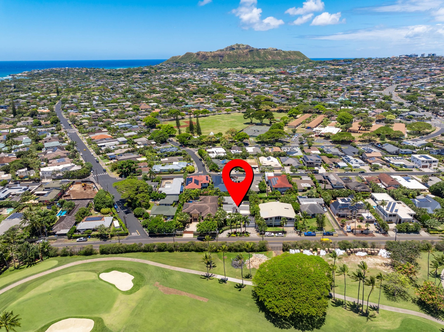 Honolulu Vacation Rentals, Ho'okipa Villa - Aerial view of the property nestled in a coastal residential neighborhood, positioned near a golf course with ocean and mountain views in the surrounding area.