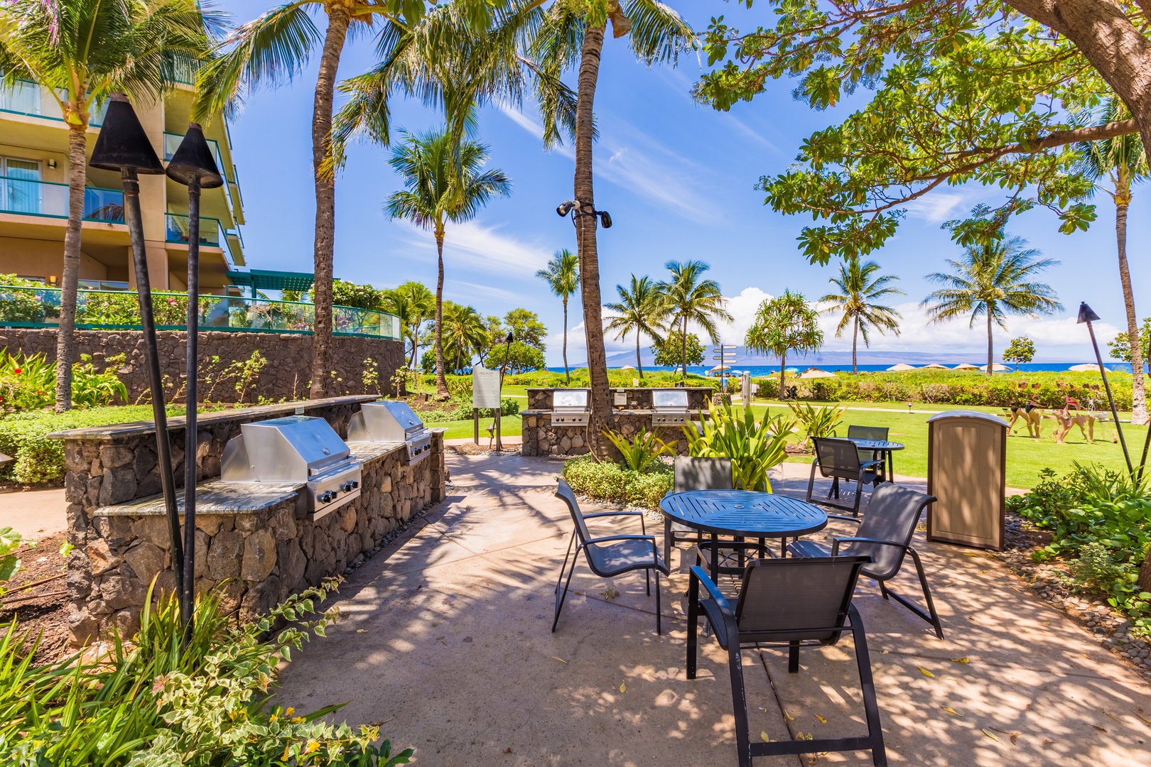 HI Vacation Rentals, Honua Kai Hokulani 825 - Enjoy an outdoor meal in paradise, with barbecue grills and dining areas set amidst swaying palm trees and ocean views.