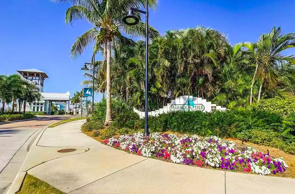 Welcome to Harbour Isle, a tropical paradise with lush palms and vibrant flowers marking the entrance to this waterfront community.
