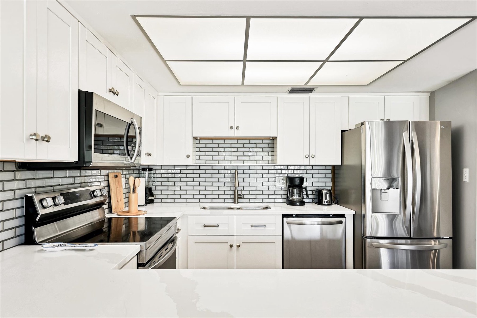 Your sleek kitchen awaits with stainless steel appliances, white cabinets, and subway tile backsplash—perfect for preparing meals during your stay.