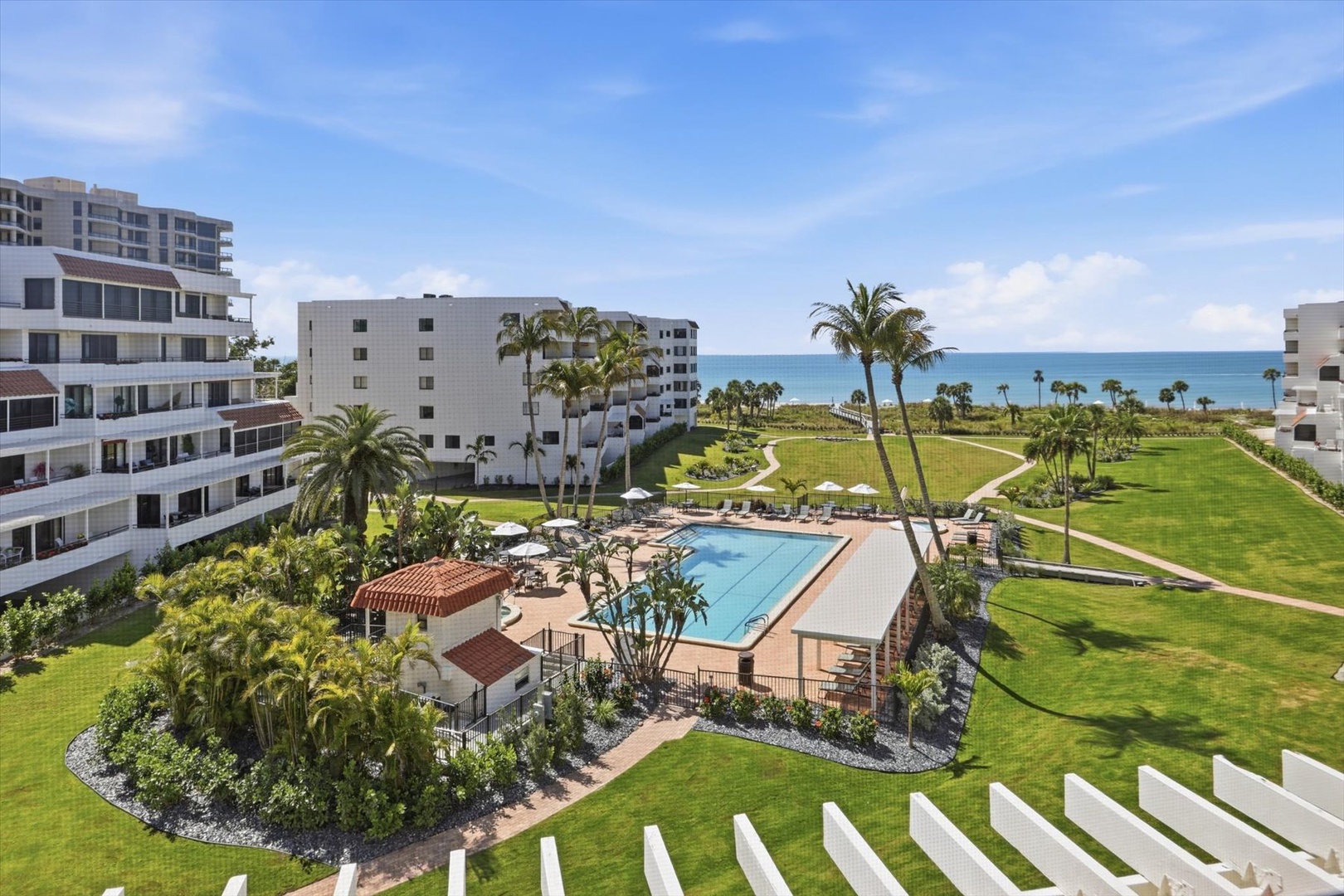 Resort complex with palm-lined pool area, manicured lawns, and direct beach access creating an ideal coastal vacation destination.