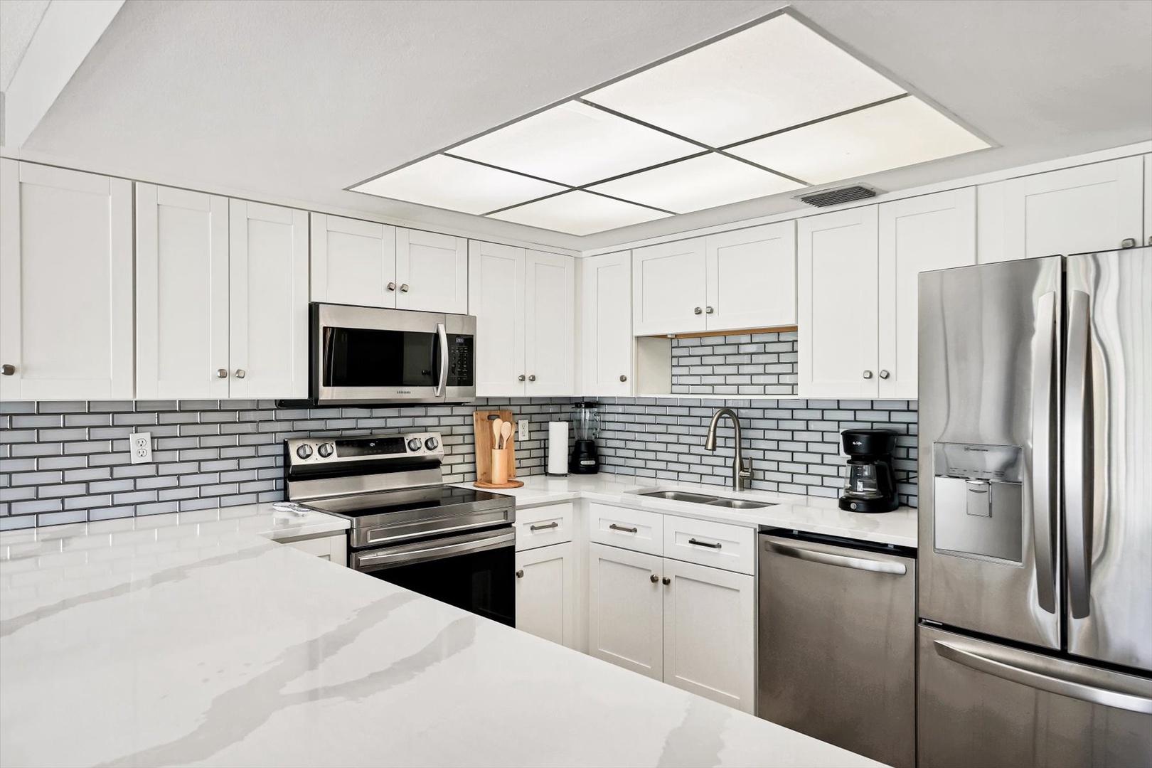 Step into your beautifully renovated kitchen with gleaming stainless steel appliances, elegant white cabinetry, and stylish subway tile backsplash.