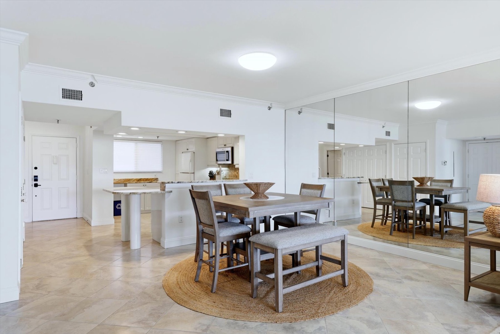 Your spacious open-plan living area flows seamlessly from kitchen to dining, with gleaming floors and mirrored walls amplifying the bright, airy feel.