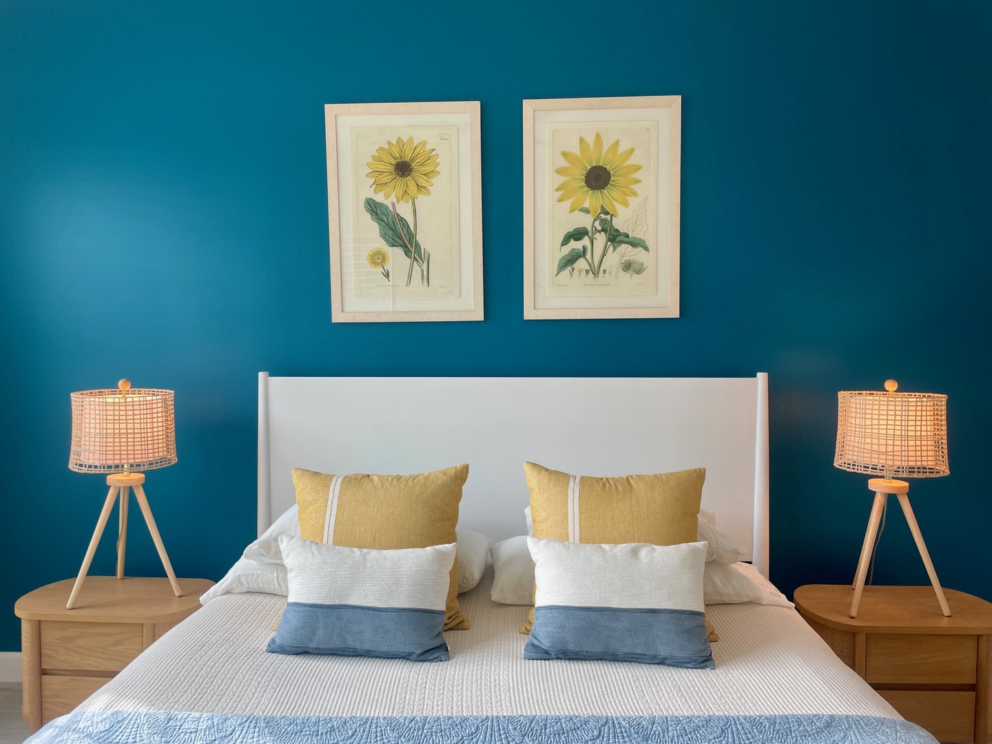 Sink into soft bedding beneath cheerful botanical art in your bright, cozy retreat with warm wood furnishings.