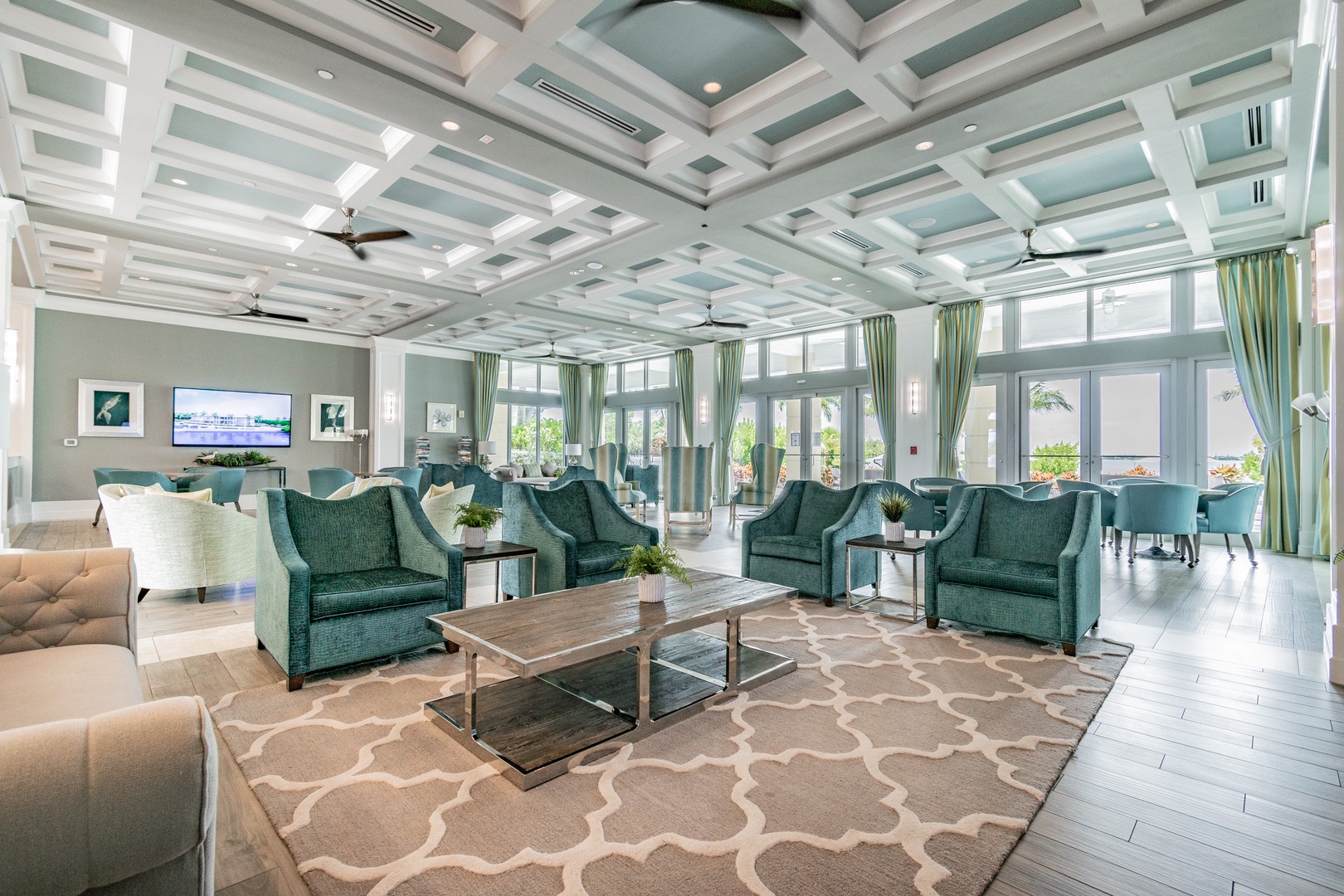 Relax in this elegant communal lounge with plush seating, stunning coffered ceilings, and floor-to-ceiling windows showcasing beautiful views.