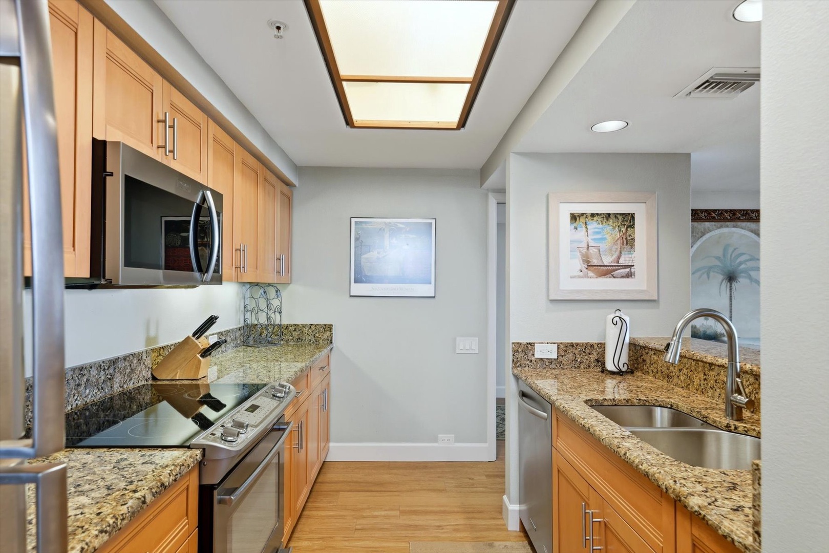 Your fully-equipped galley kitchen features granite countertops, stainless steel appliances, and a bright skylight overhead for natural cooking light.