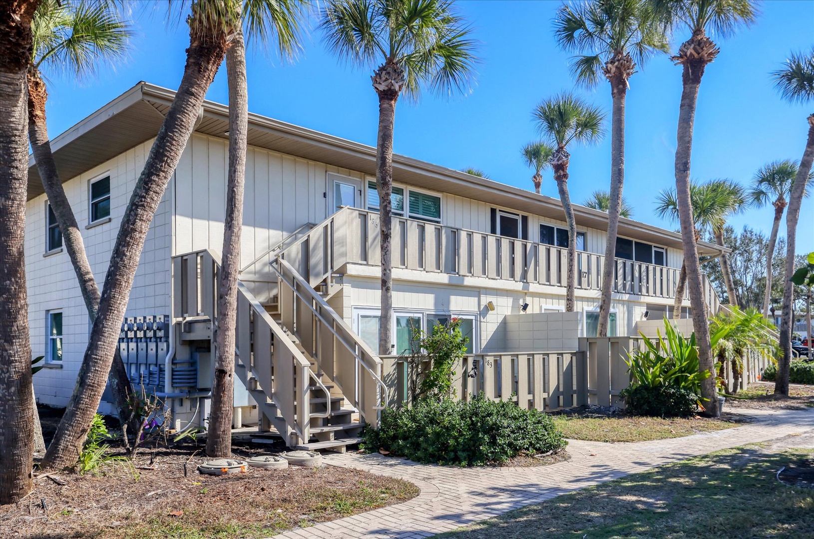 Charming beachside cottage nestled among swaying palm trees with peaceful tropical landscaping and convenient ground-level access.