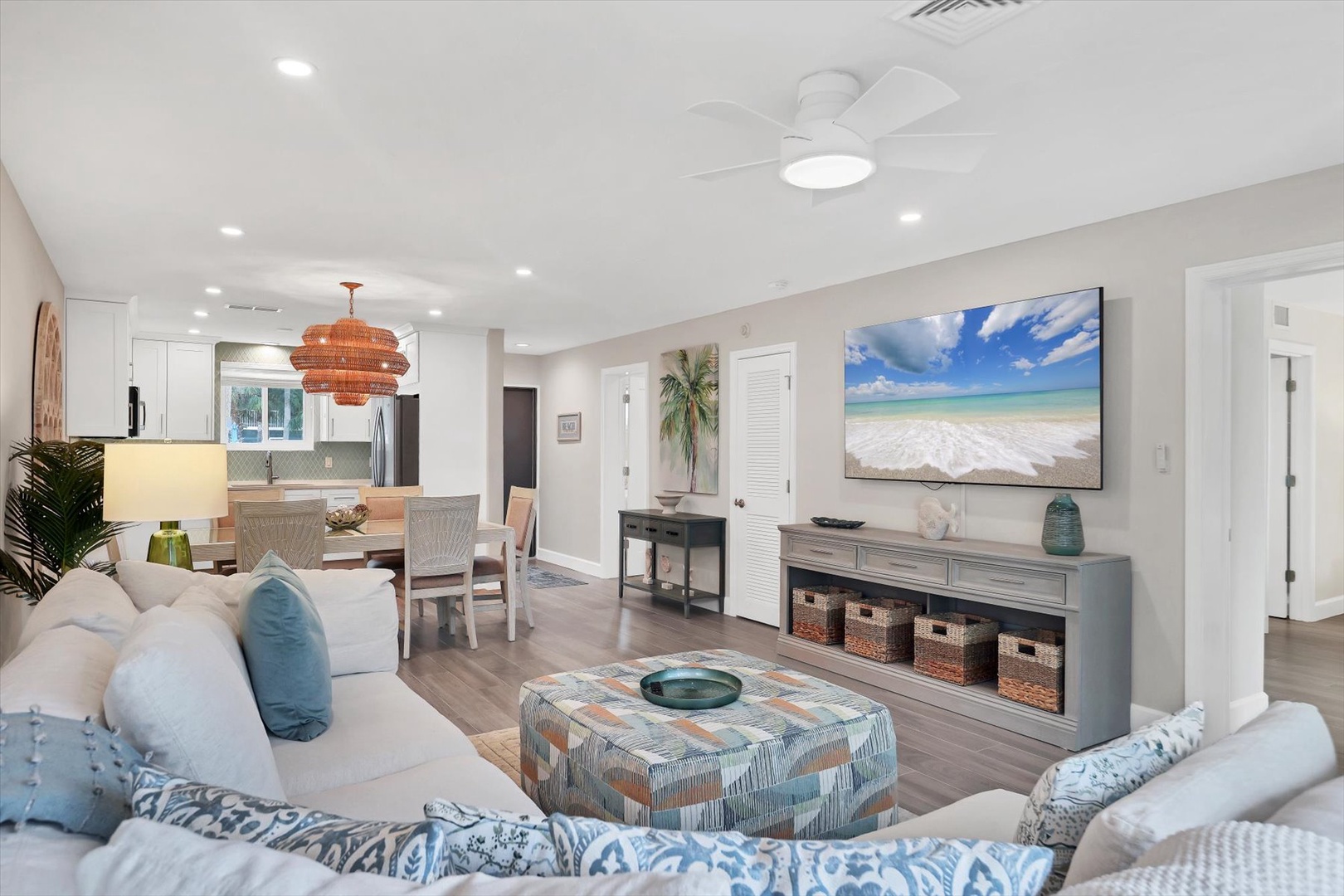 Relax in your coastal-inspired living space with plush seating, tropical artwork, and a ceiling fan keeping you cool.