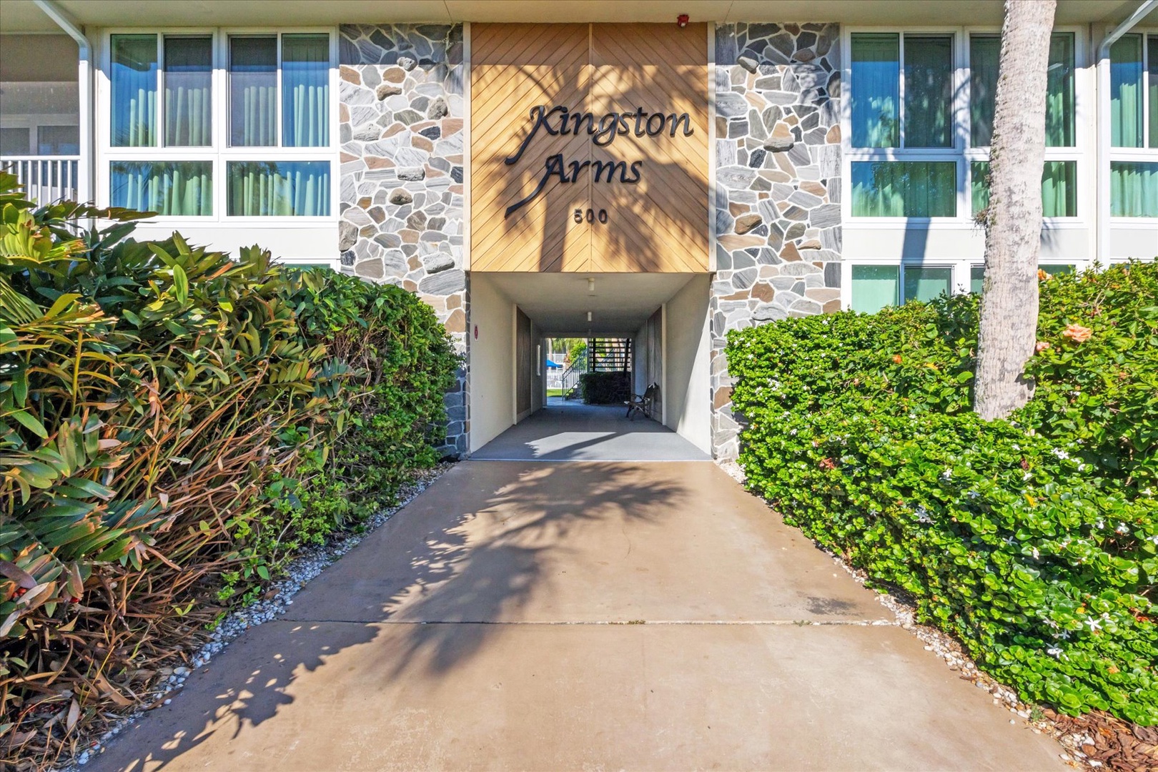 The welcoming entrance to Kingston Arms features tropical landscaping and stone accents, marking your arrival at this peaceful retreat.